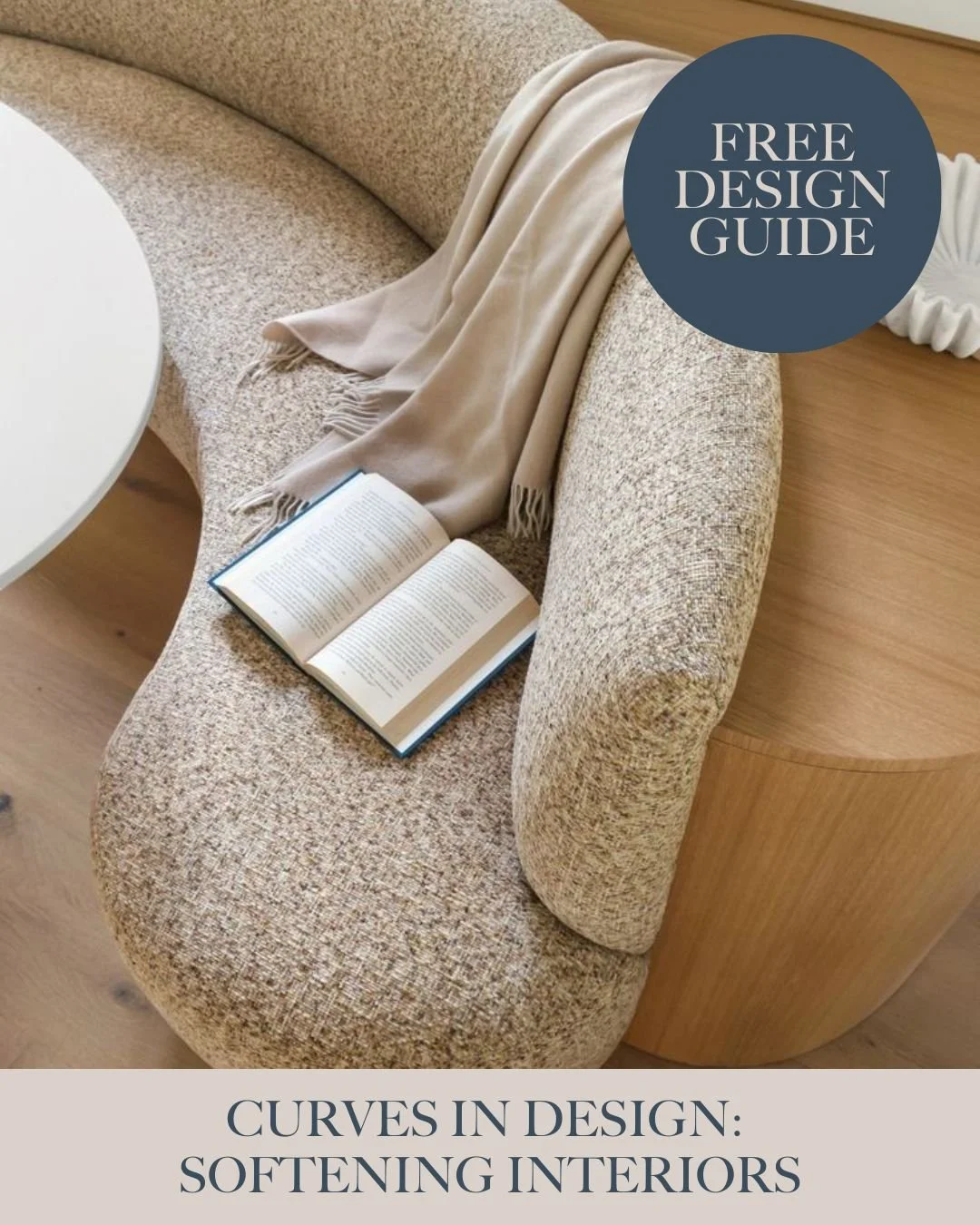 A beige curved sofa with a beige throw blanket and an open book resting on it, alongside a small white side table, with a circular blue graphic saying 'Free Design Guide' and text at the bottom reading 'Curves in Design: Softening Interiors'.