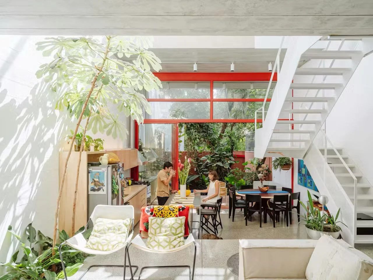 This home feels like a masterclass in contrast done well. 

We love the tension here: raw concrete against warm timber, dramatic scale softened by collected pieces, bold red window frames cutting through an otherwise earthy, muted palette. Indoor and