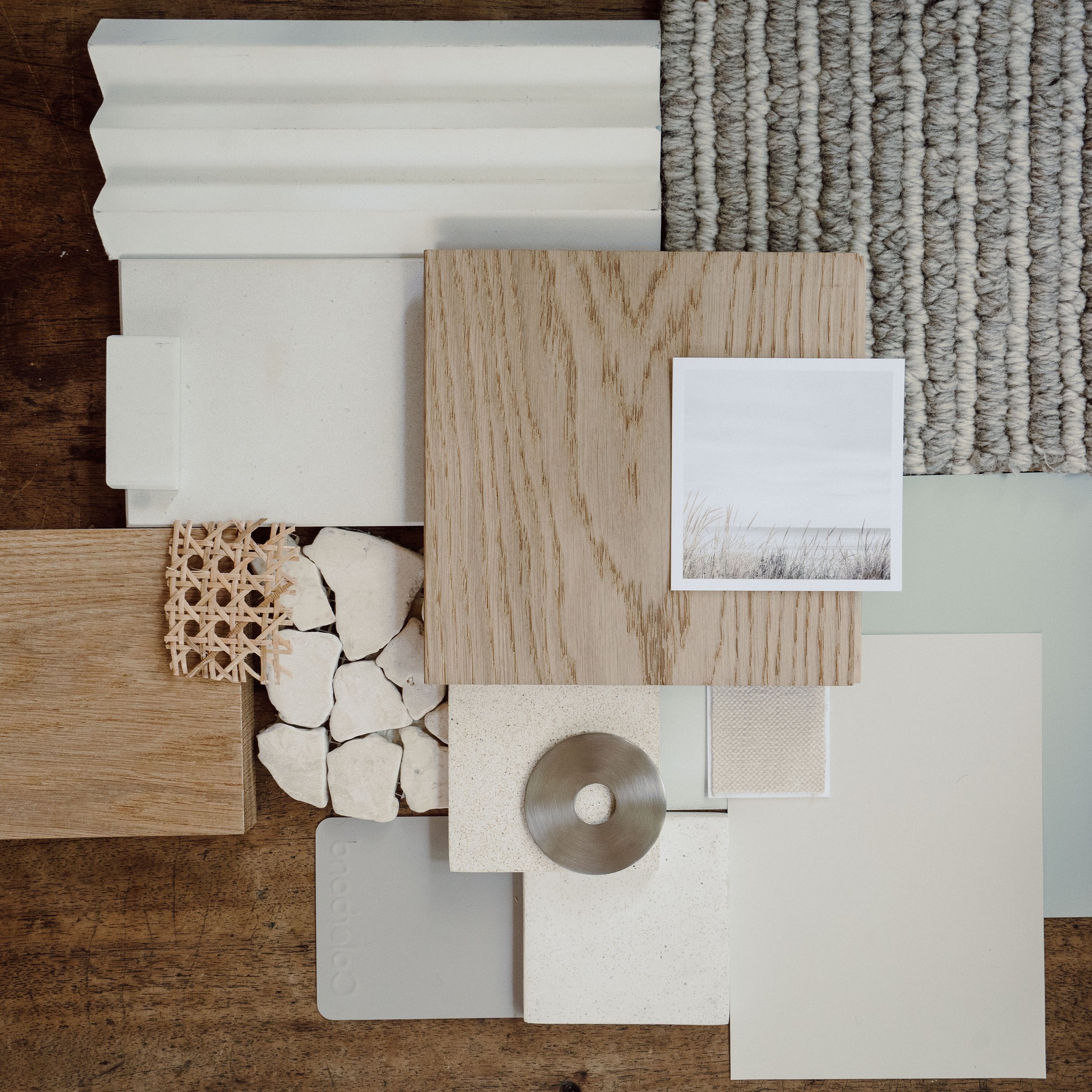 A collection of interior design material samples including wood, fabric, stone, and paint swatches, along with a black and white photograph of a landscape.