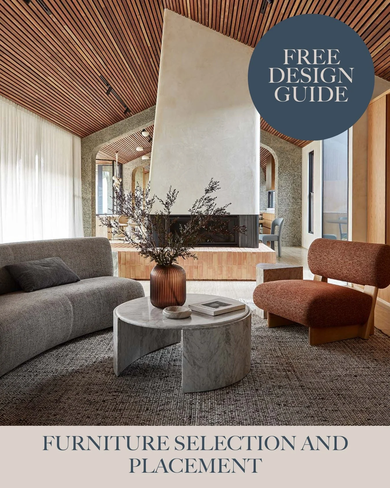 Living room with a gray sofa, a rust-colored chair, a round marble coffee table with a vase of dried branches, and a fireplace with a modern design in a contemporary open-plan interior with wood accents and large windows.