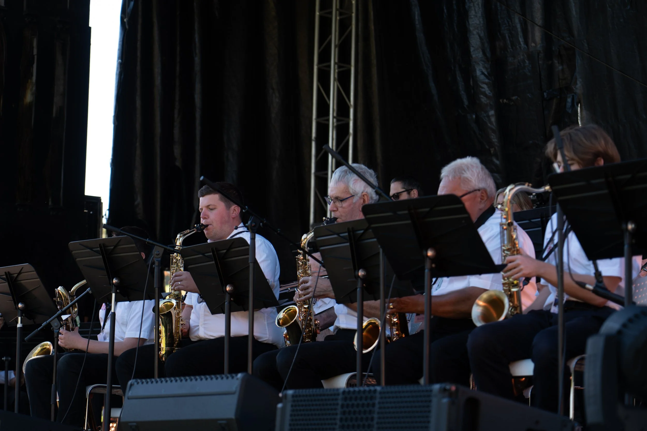 A group of musicians playing saxophones on stage during a performance. Hawkes Bay Jazz Club Big Band. Jazz In the park church road winery.