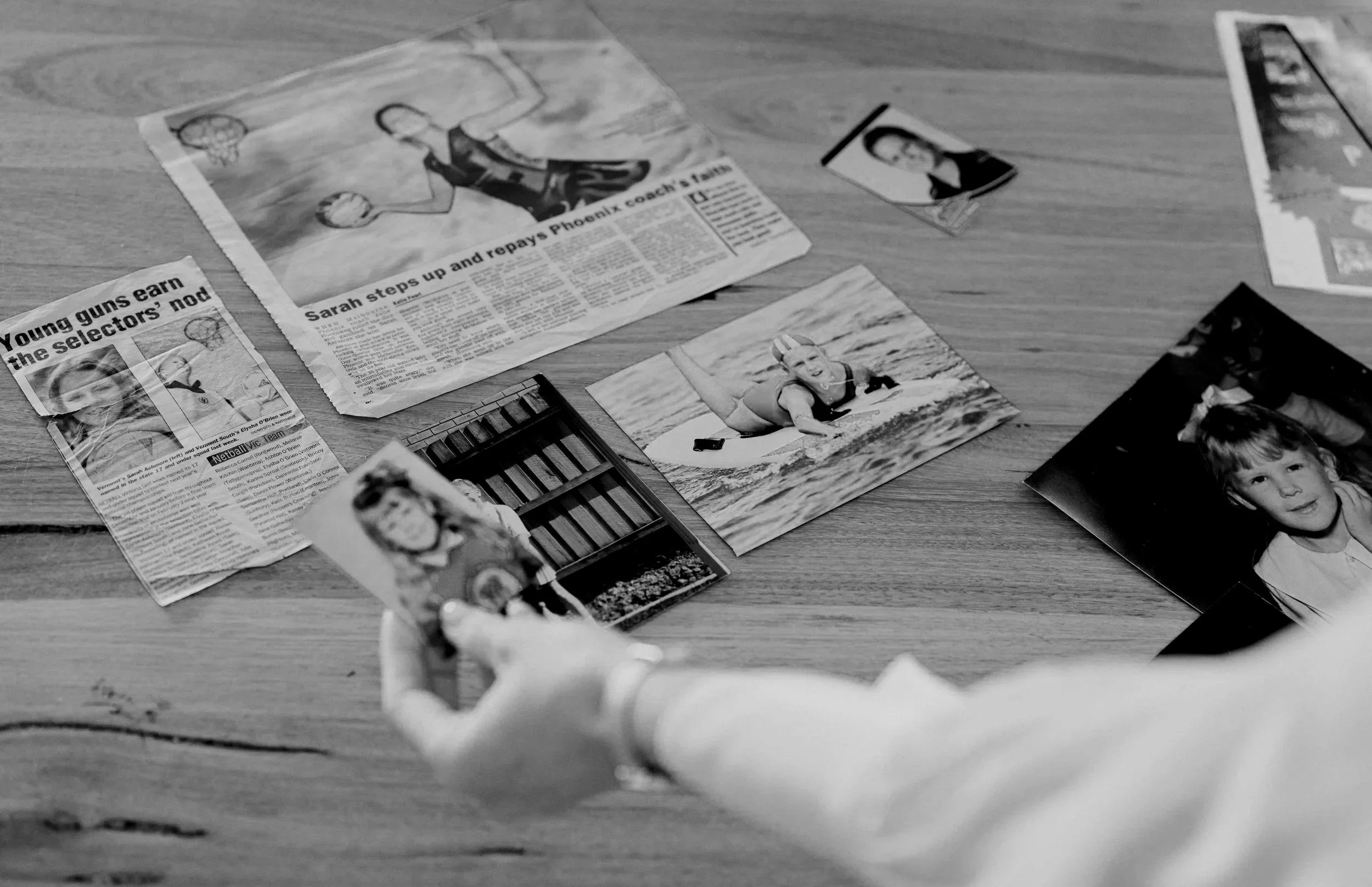 Sarah Ashmore holding looking through childhood images that contribute to her personal story through netball, the media and now running her own business.