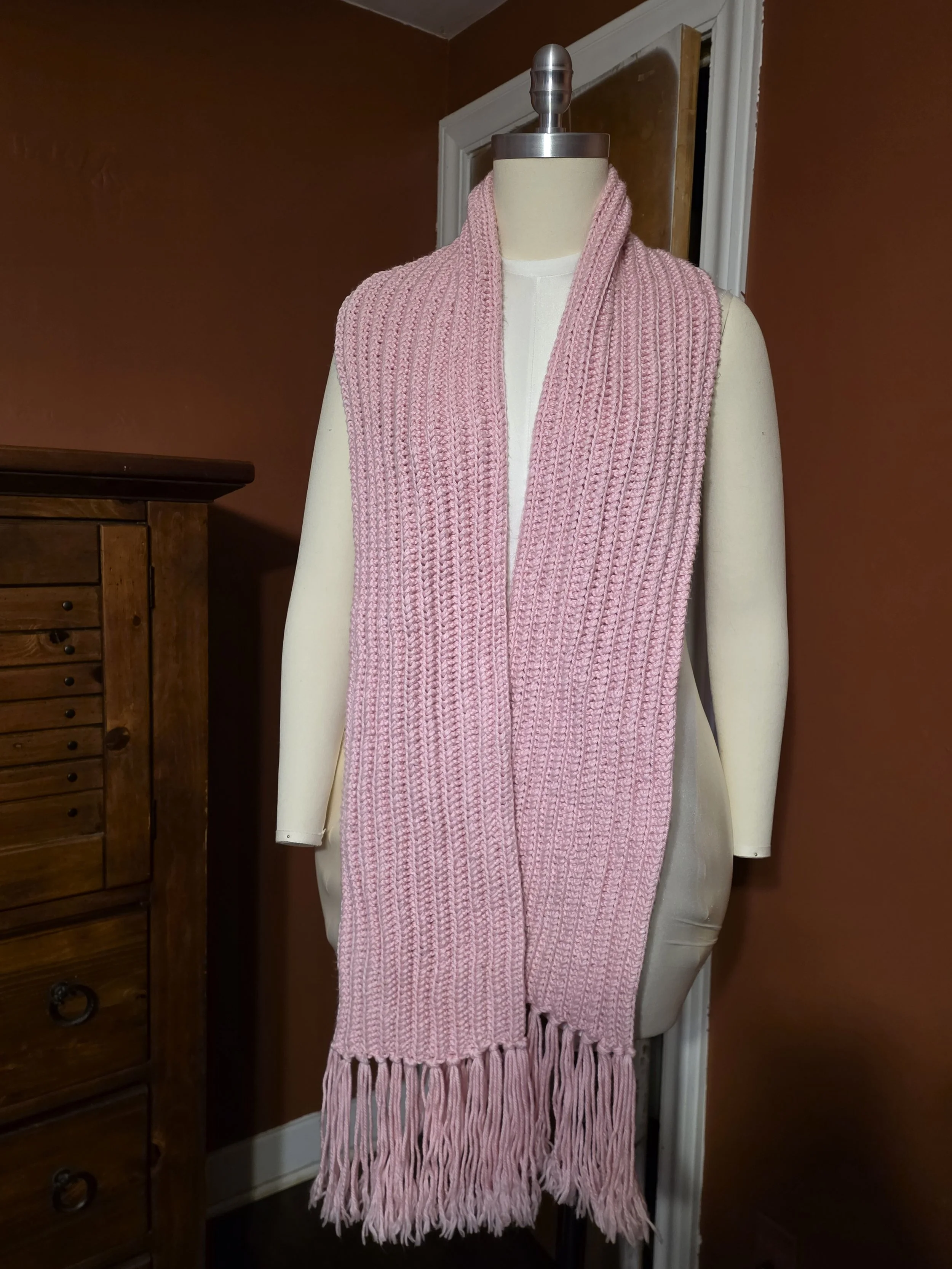 Handmade custom lacy scarf in pink, draped straight with tassels on dress form