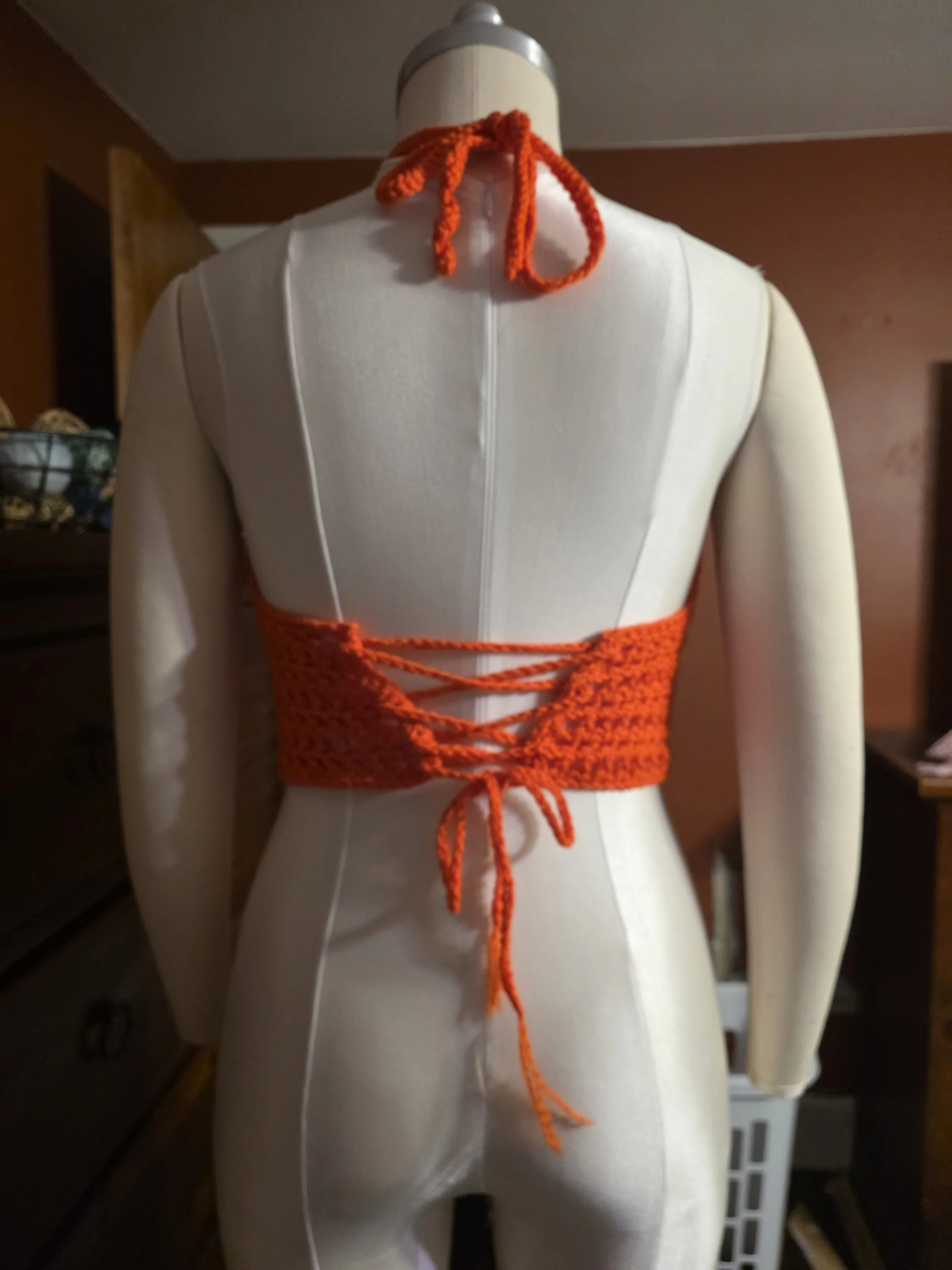 Handmade crochet mesh top back view in orange on dress form close-up