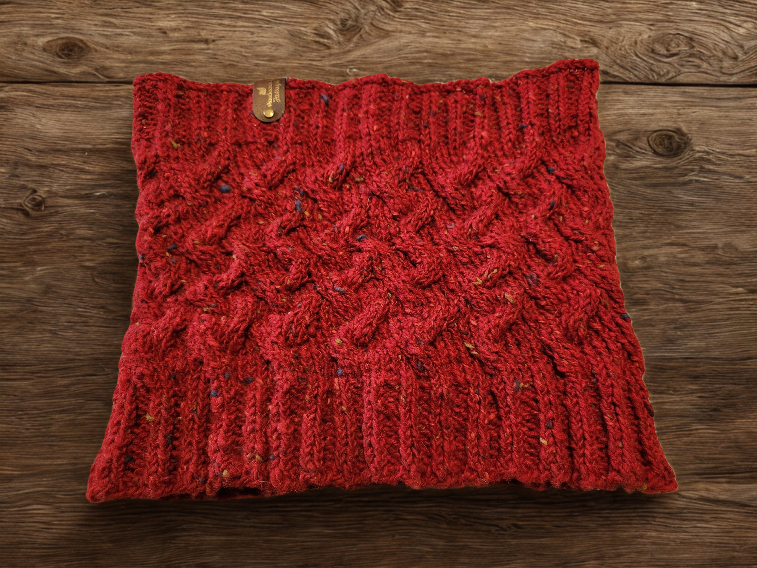 Handmade knitted cabled cowl in red, flat lay view