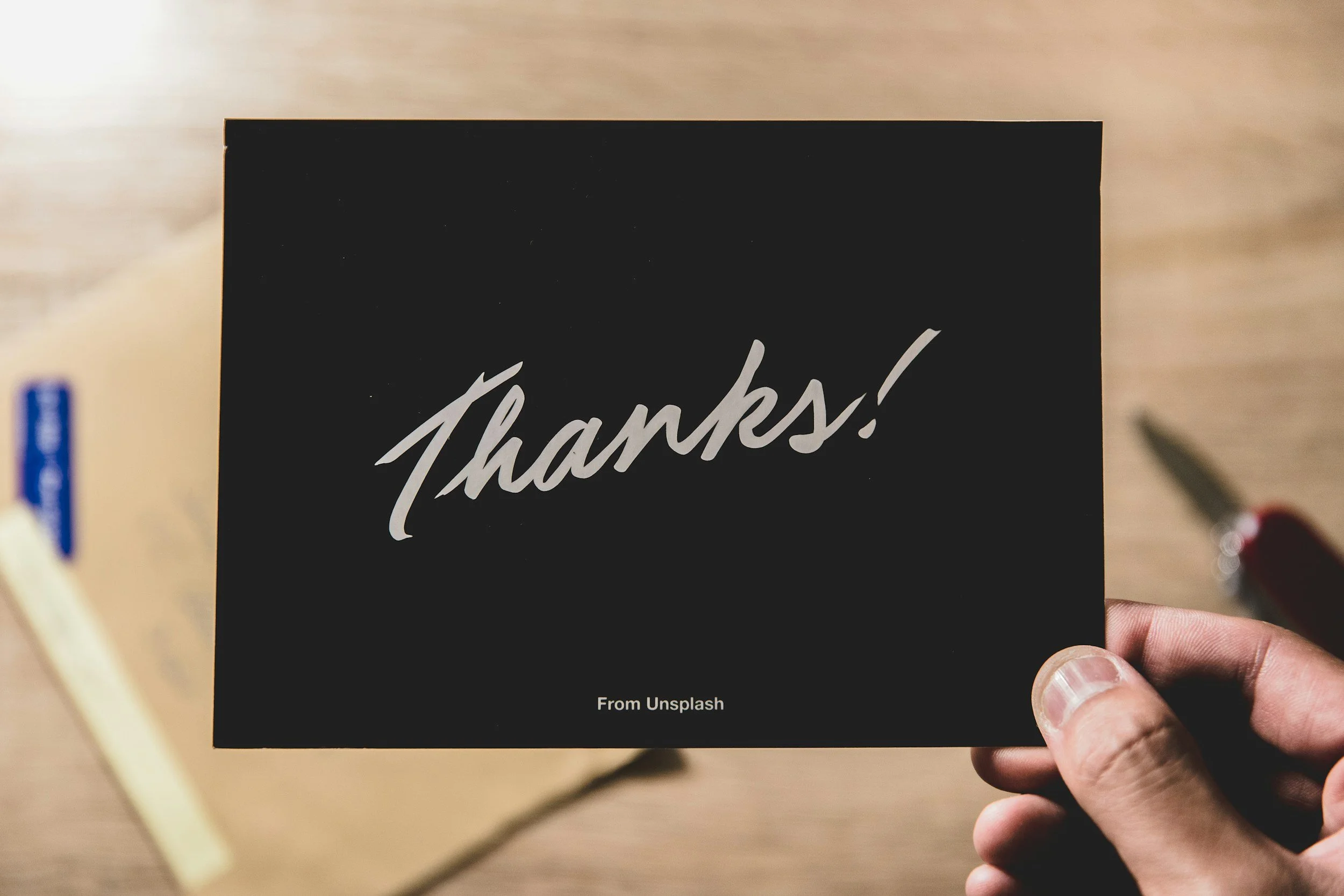 A black card with white handwritten-style text that says 'Thanks!' and smaller text below that reads 'From Unsplash.'