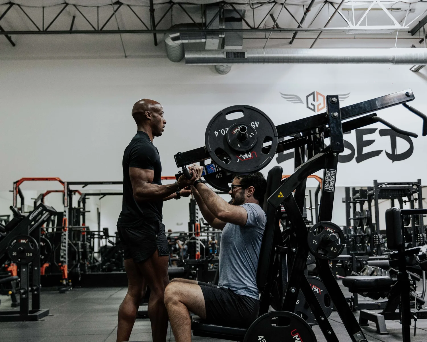 Akram coaching a client through a barbell lift