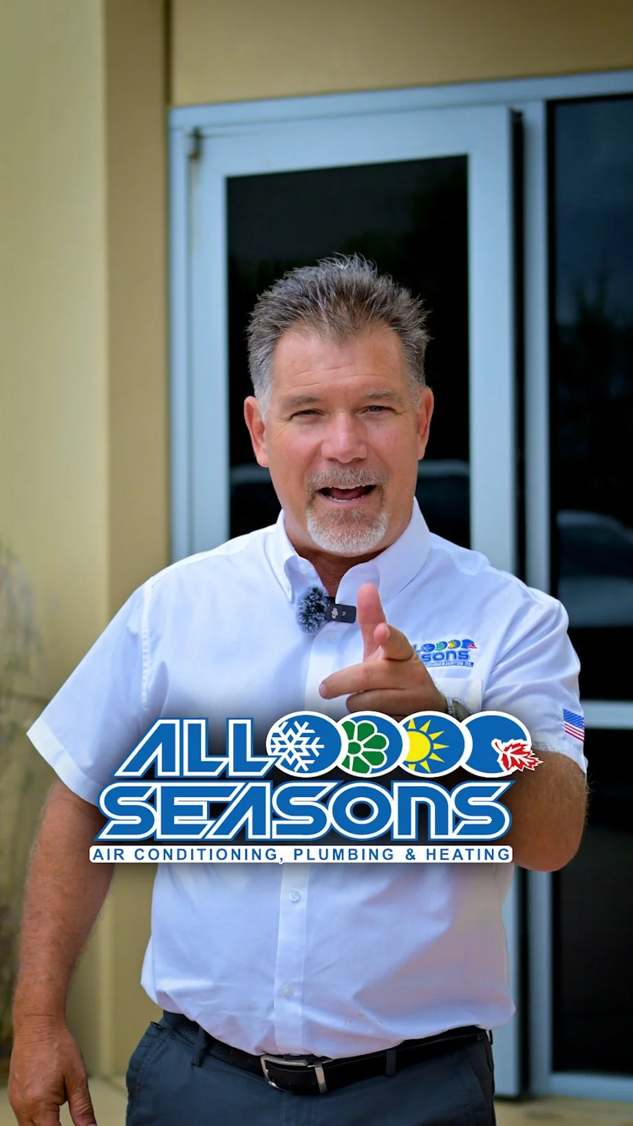 A man wearing a white shirt with an 'All 4 Seasons' logo, pointing at the camera, standing outside near a glass door, with text overlay advertising air conditioning, plumbing, and heating services.