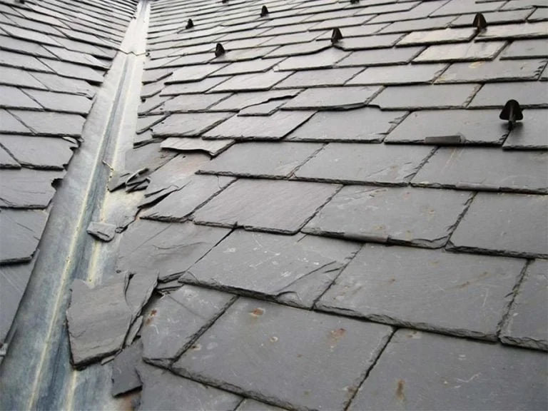 Close-up of a slate shingle roof with a metal flashing along the seam.