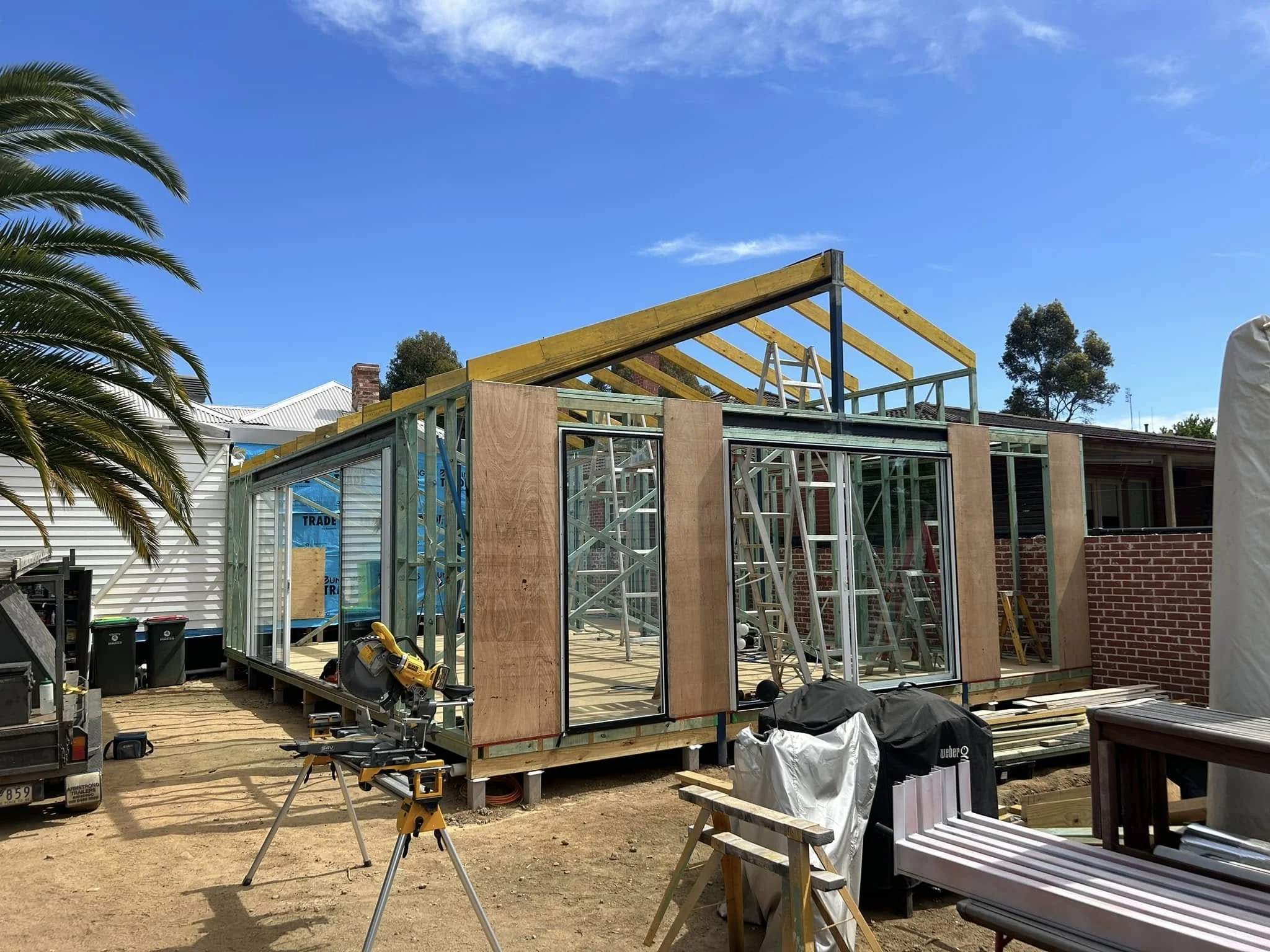 Construction site with building framework, ladders, tools, and a blue sky.