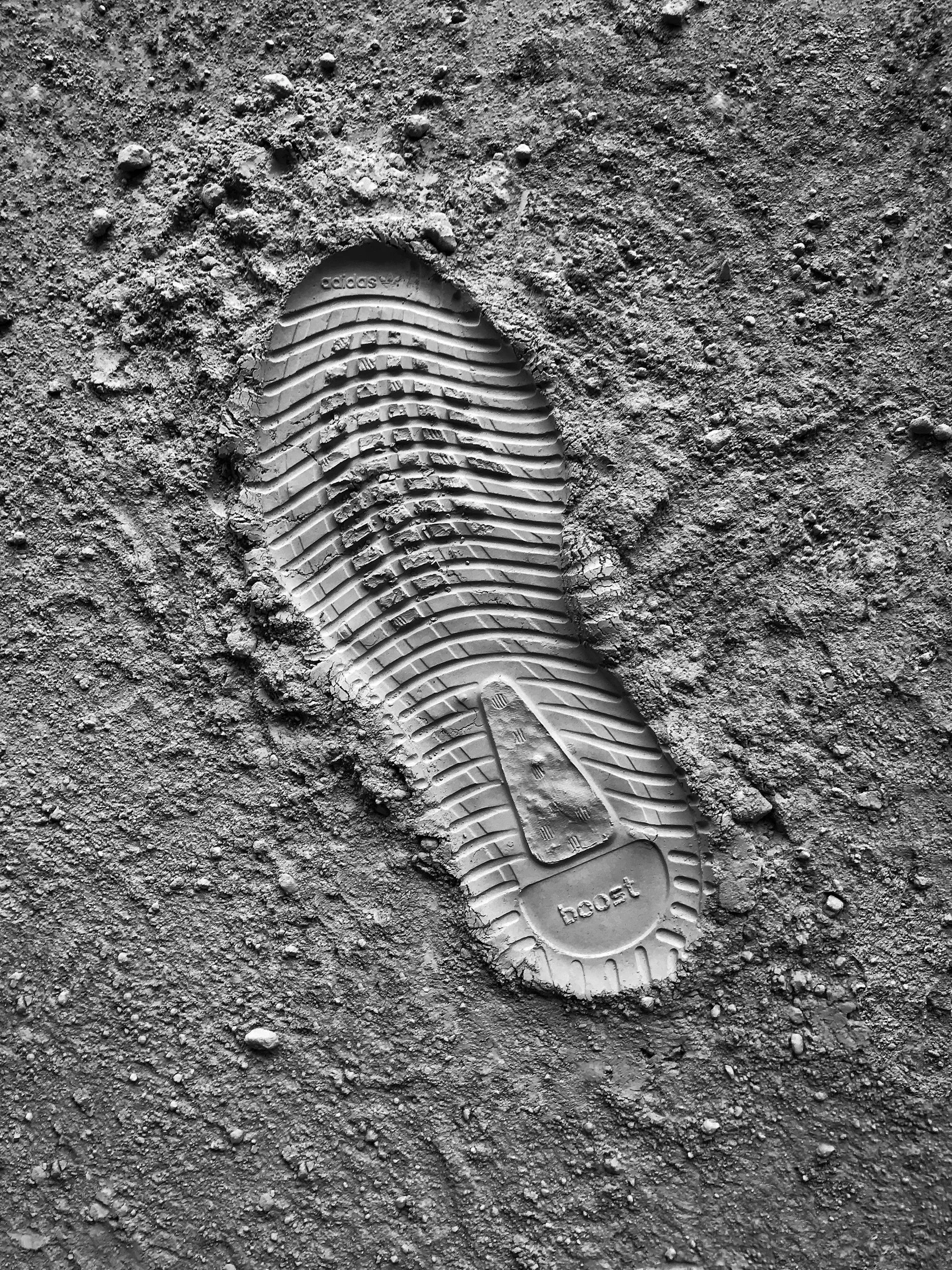 A single sneaker shoe print in the dirt, with the word 'boost' visible on the sole.