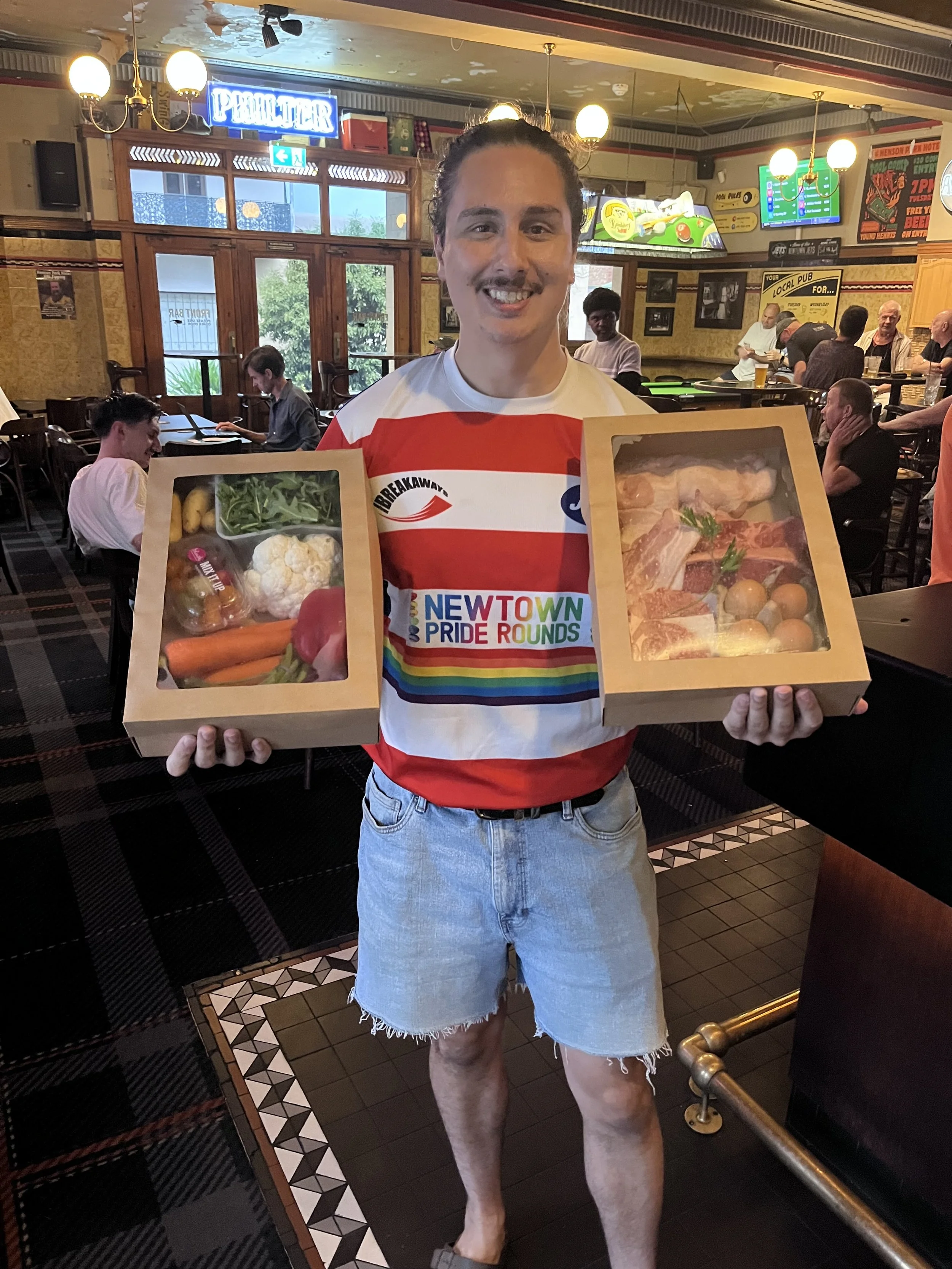 A smiling man holding cash in a bar with a spinning wheel in the background. Advertising Friday Nights with spin and win raffle with cash prizes, beer tabs, meat and vegetable trays, and a weekly jackpot of $500, starting from 6 pm at the front bar.