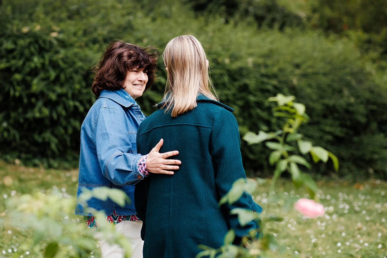 Photo de deux femmes qui marchent dans un park. La première regarde la deuxième et lui pose une main dans le dos en toute bienveillance.