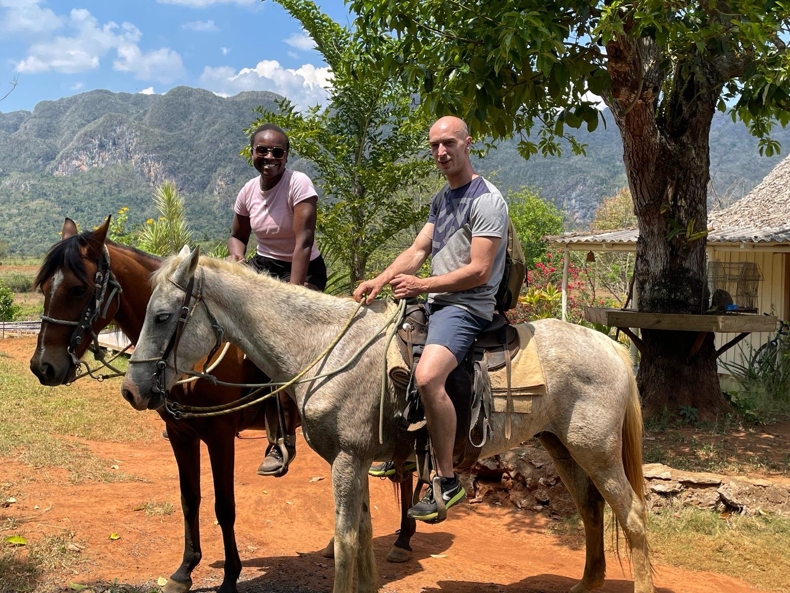 Deux personnes ravies à cheval, un homme et une femme, en plein air avec des mogotes en arrière-plan. 
