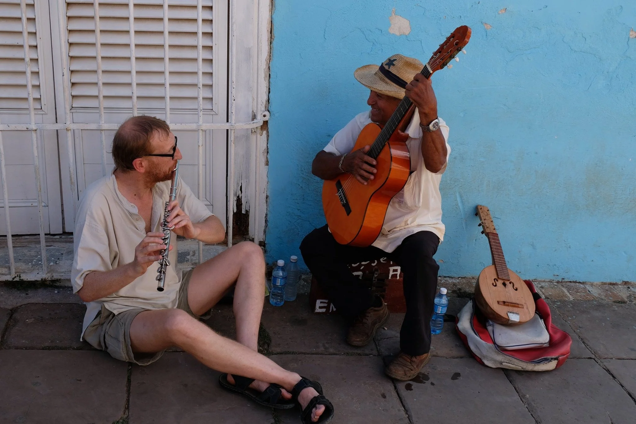 Un musicien cubain et un touriste jouent de la musique dans la rue, l'un jouant de la flûte et l'autre de la guitare, assis dans une rue de Trinidad.
