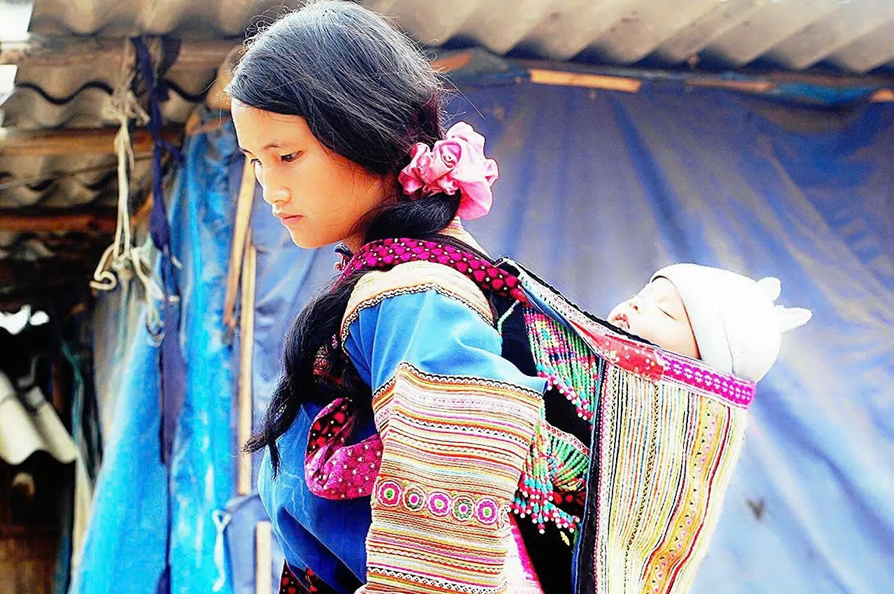 Fille hmong bariole porte son enfant.jpg