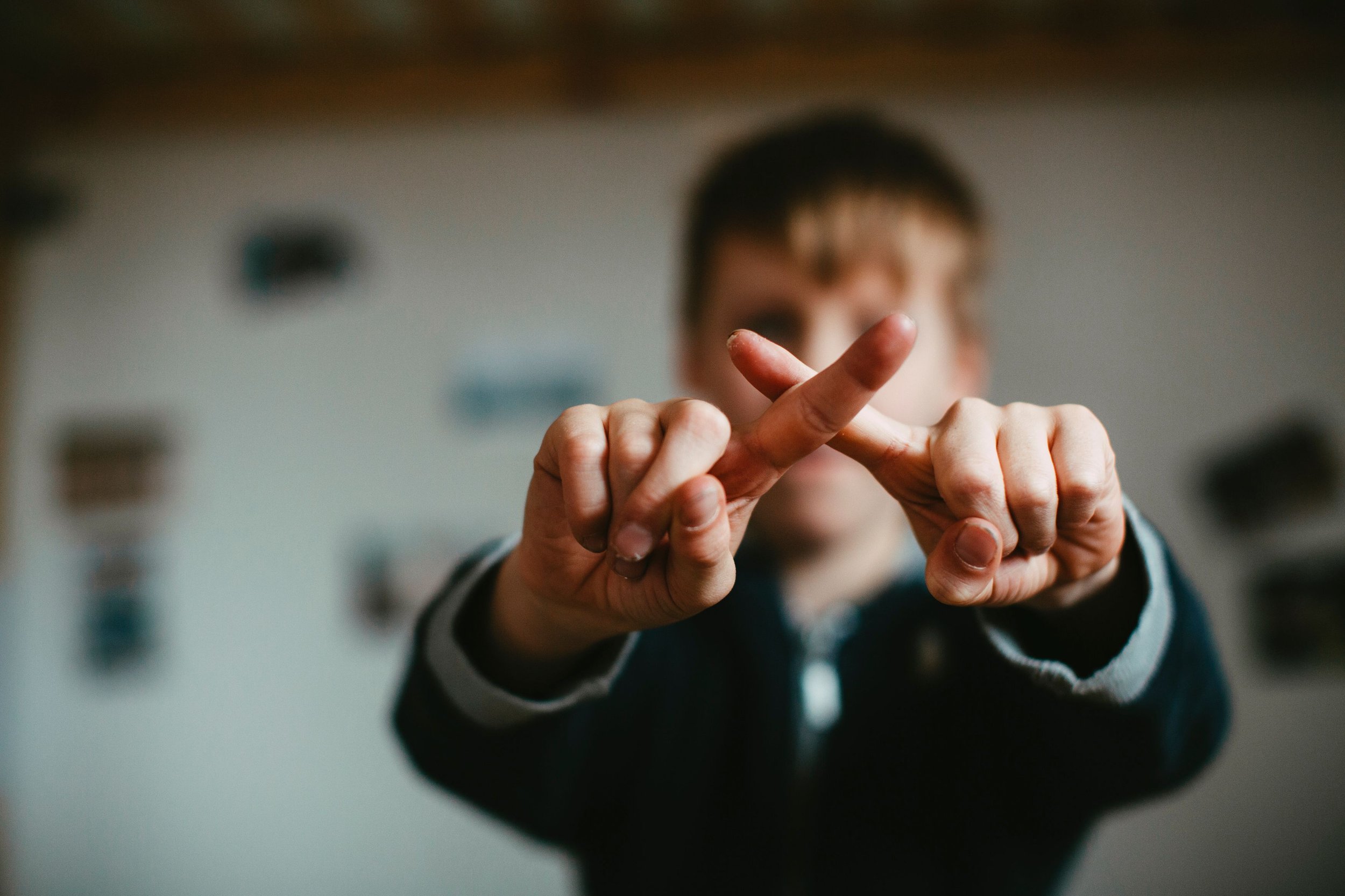a boy with two fingers crossed in an X shape