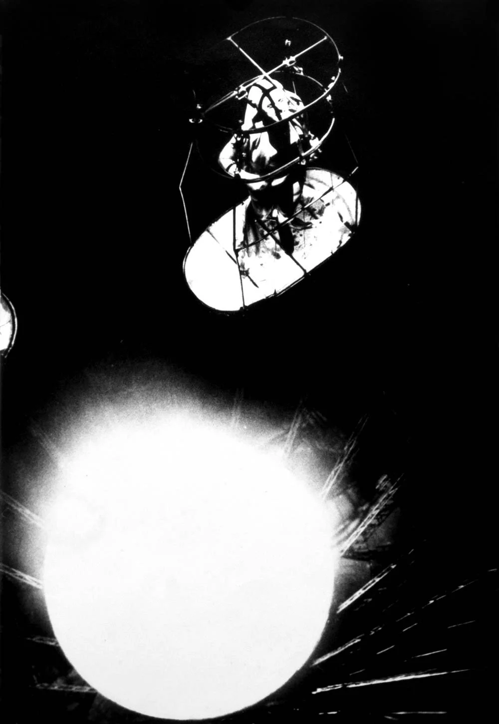 Estrutura de uma cabine de nave espacial ou satélite com refletores, no escuro, com uma grande luz forte na parte inferior.