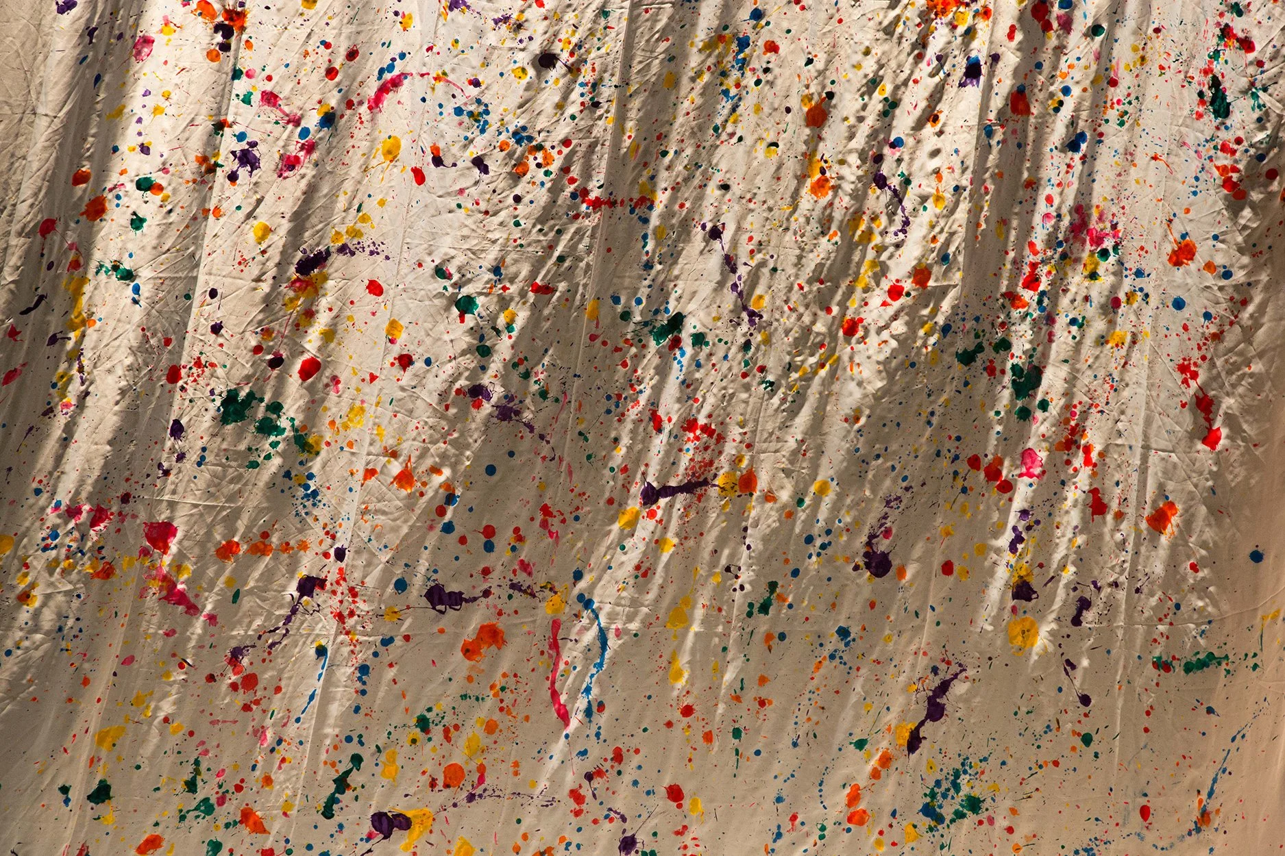 Tela com manchas de tinta colorida em várias cores, espalhadas de forma aleatória.