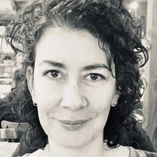 Retrato de uma mulher com cabelo cacheado, sorrindo, em preto e branco.