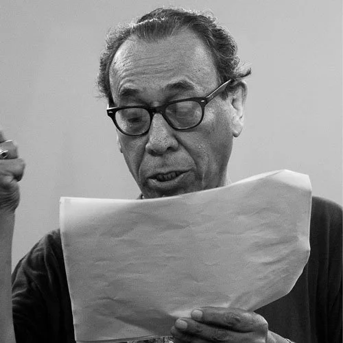 Homem com óculos lendo uma folha de papel