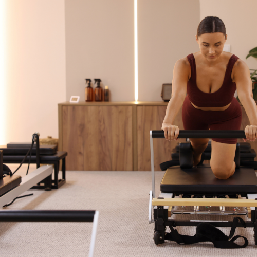 Woman doing Pilates on a reformer machine in a fitness studio.