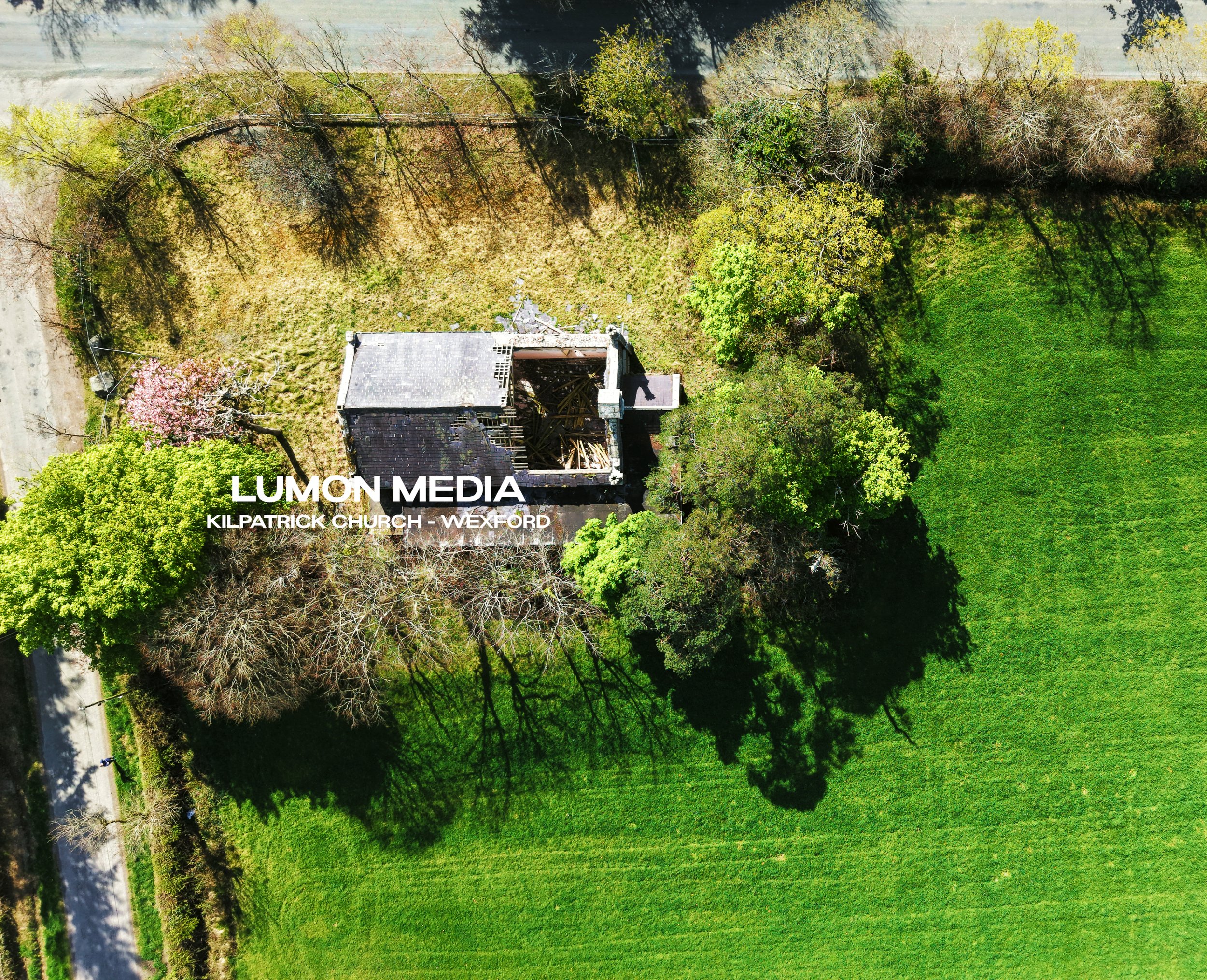Aerial view of Kilpatrick Church in Wexford, surrounded by green grass and trees, with part of the church building under construction or repair.