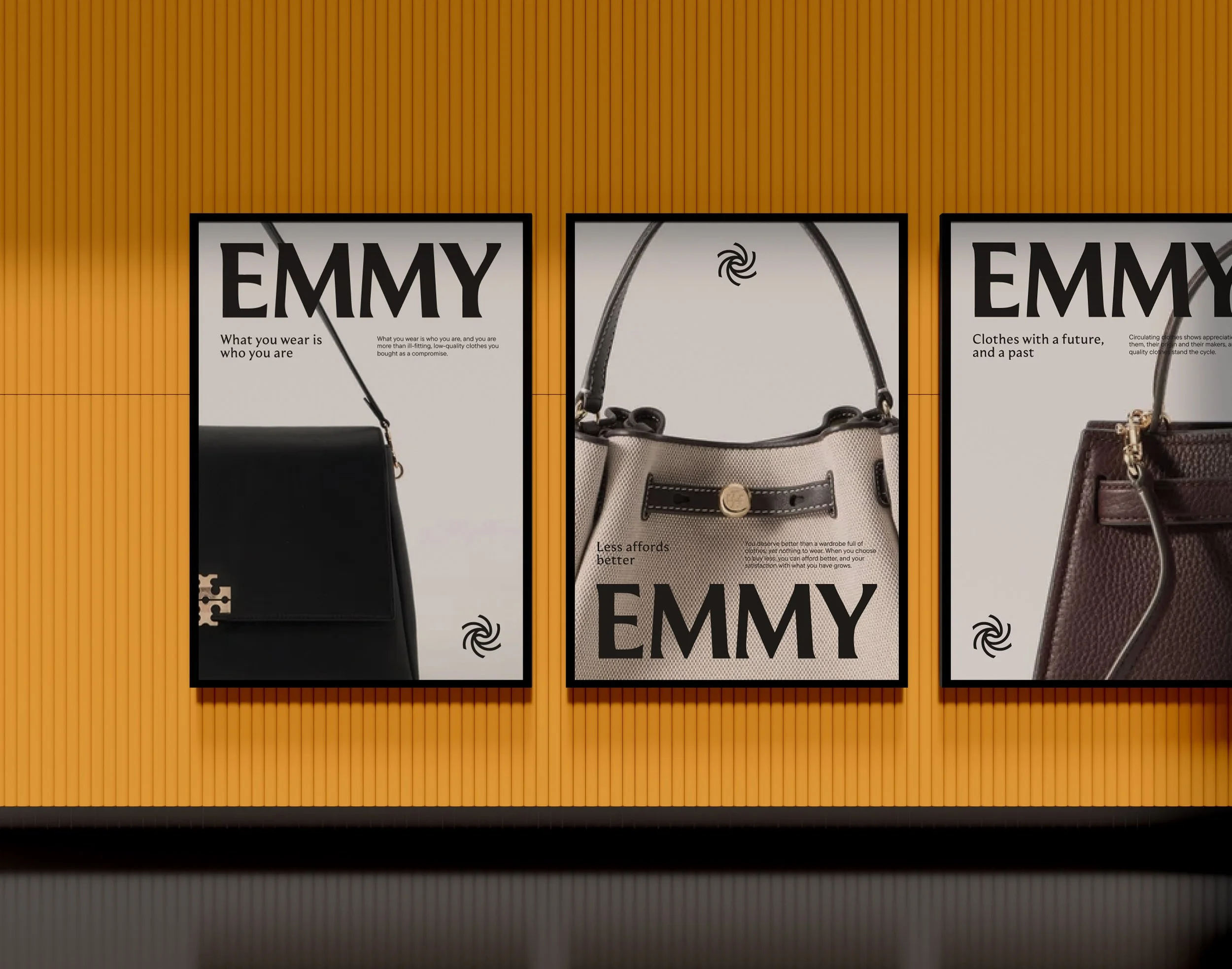 Three large posters on a vibrant yellow wall. The posters feature close-up photographs of handbags, a prominent "Emmy" wordmark, the brand's logo symbol, and blocks of narrative text telling the story of the Emmy brand.