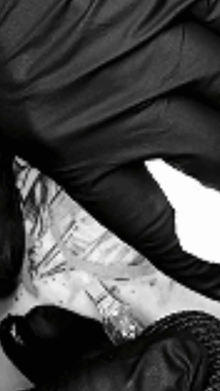 Partie inférieure d'une personne portant un pantalon noir et un vêtement noir, assise ou allongée avec un fond blanc et gris.