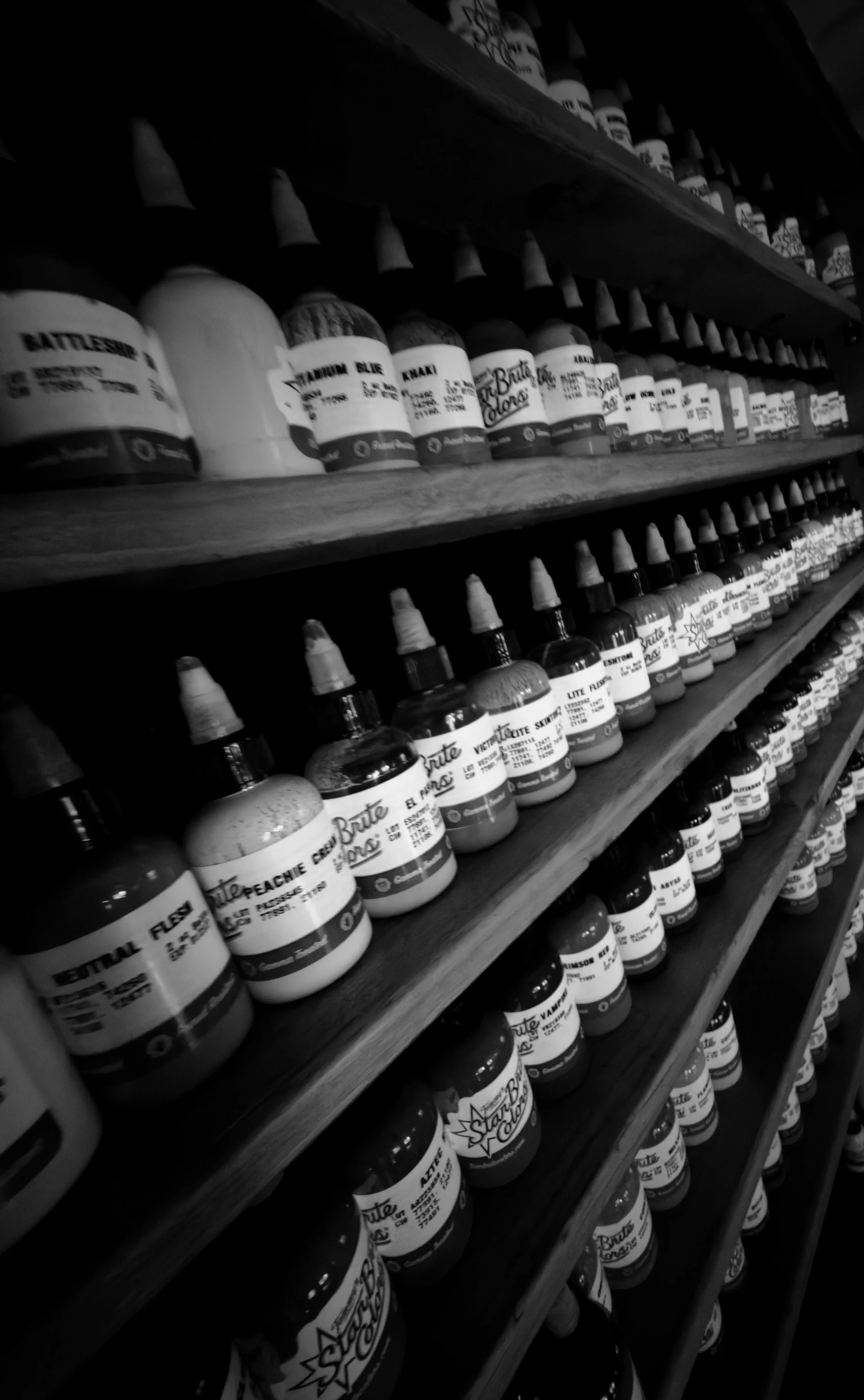 Étagères remplies de petites bouteilles de peinture ou d'encre avec étiquettes en français