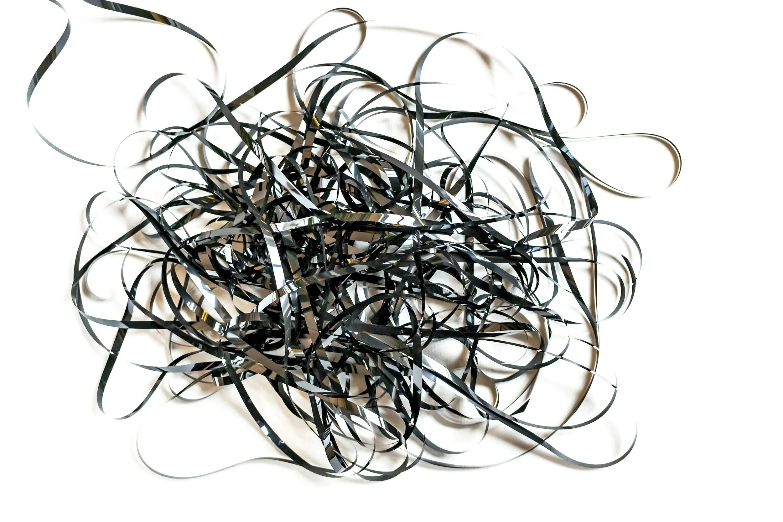 A tangled mess of black and silver metallic strips on a white background.