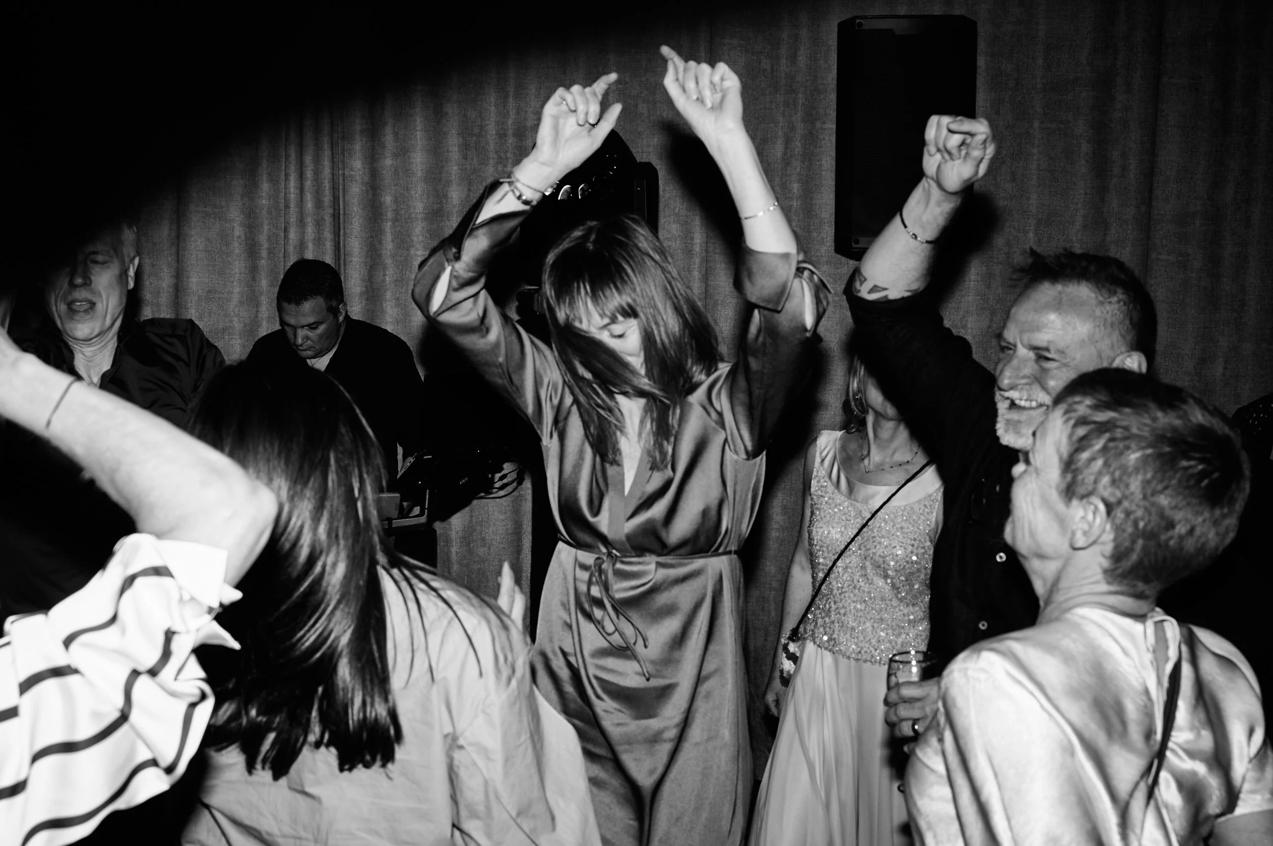 People dancing and socializing at a party or celebration, black and white photo, with some holding drinks.