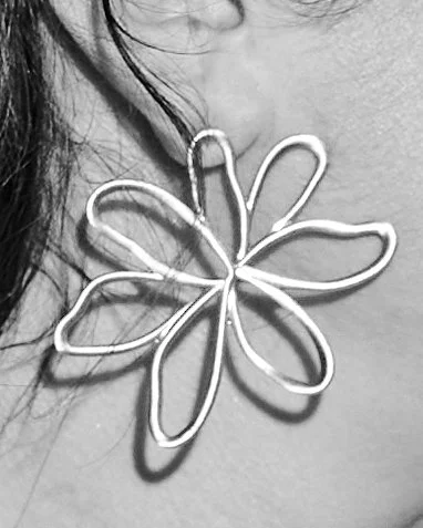 A close-up of a person's neck and shoulder with a large necklace shaped like a flower with daisy-like petals.