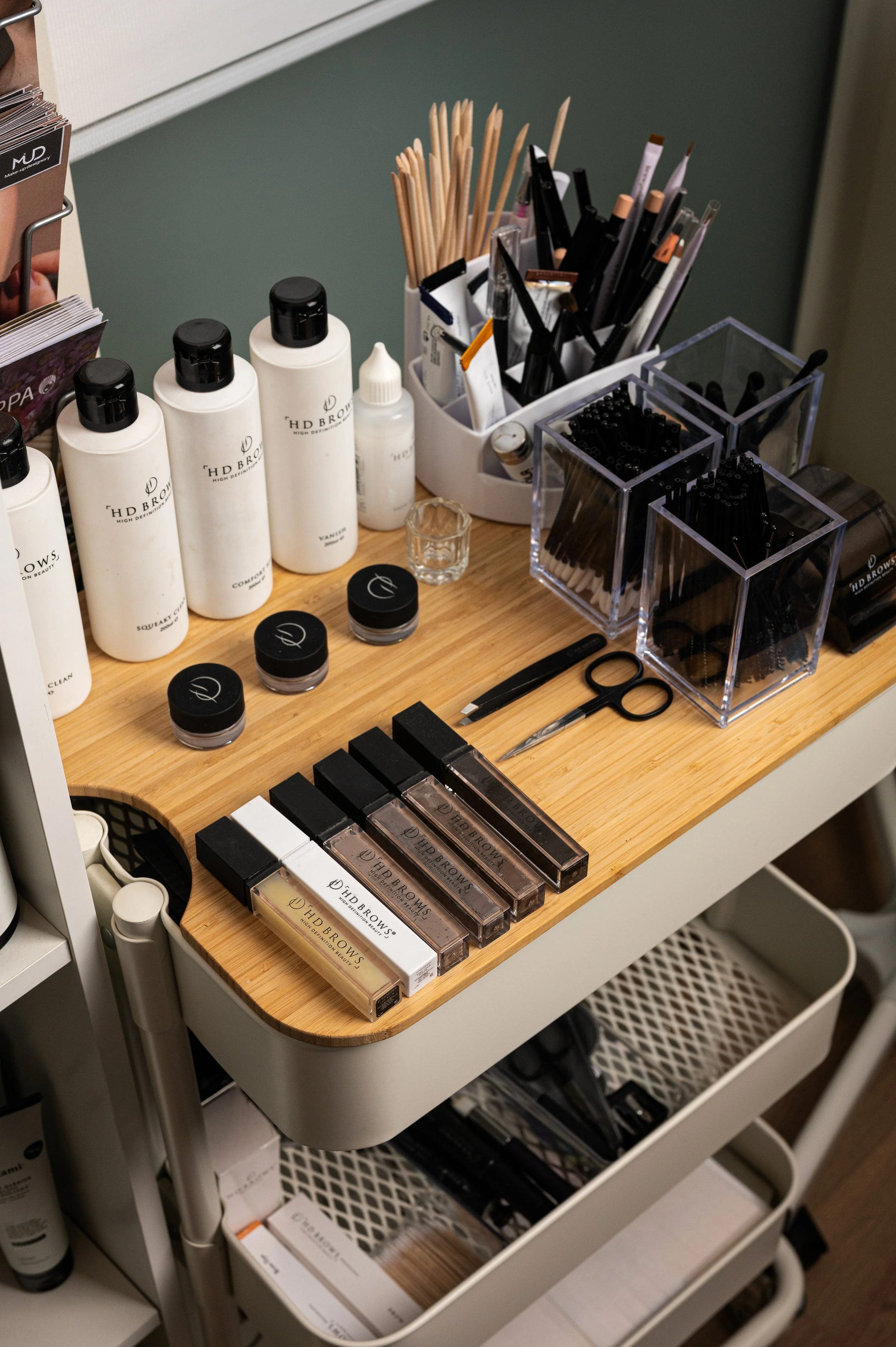 A makeup station with various cosmetic products, brushes, and tools on a wooden table.