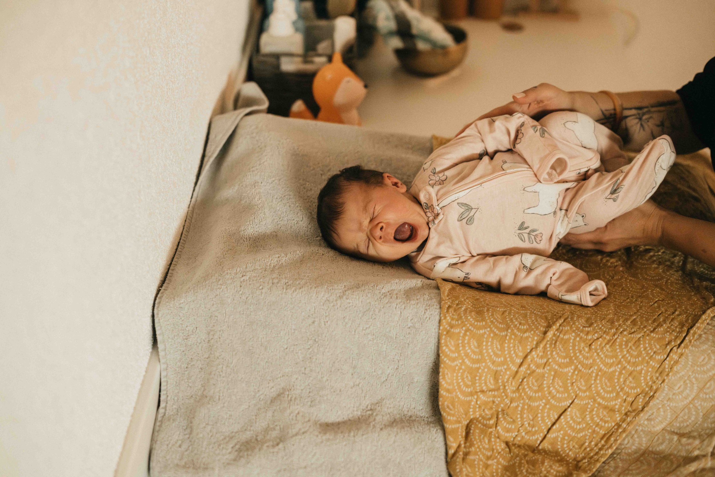 Ein schreiendes Baby, das auf einer Couch liegt.