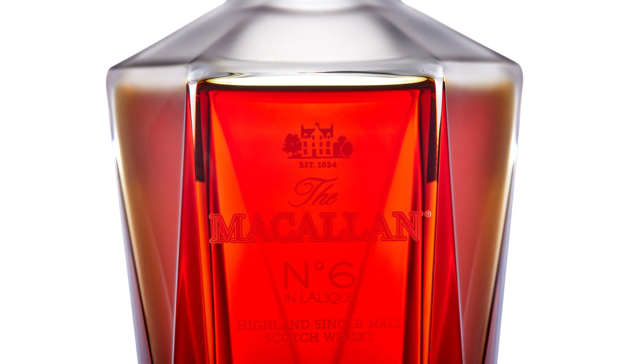 A close-up of a glass of The Macallan No. 6 Highland Single Malt Scotch Whiskey, showcasing the red liquid inside the elegant glass with detailed label.