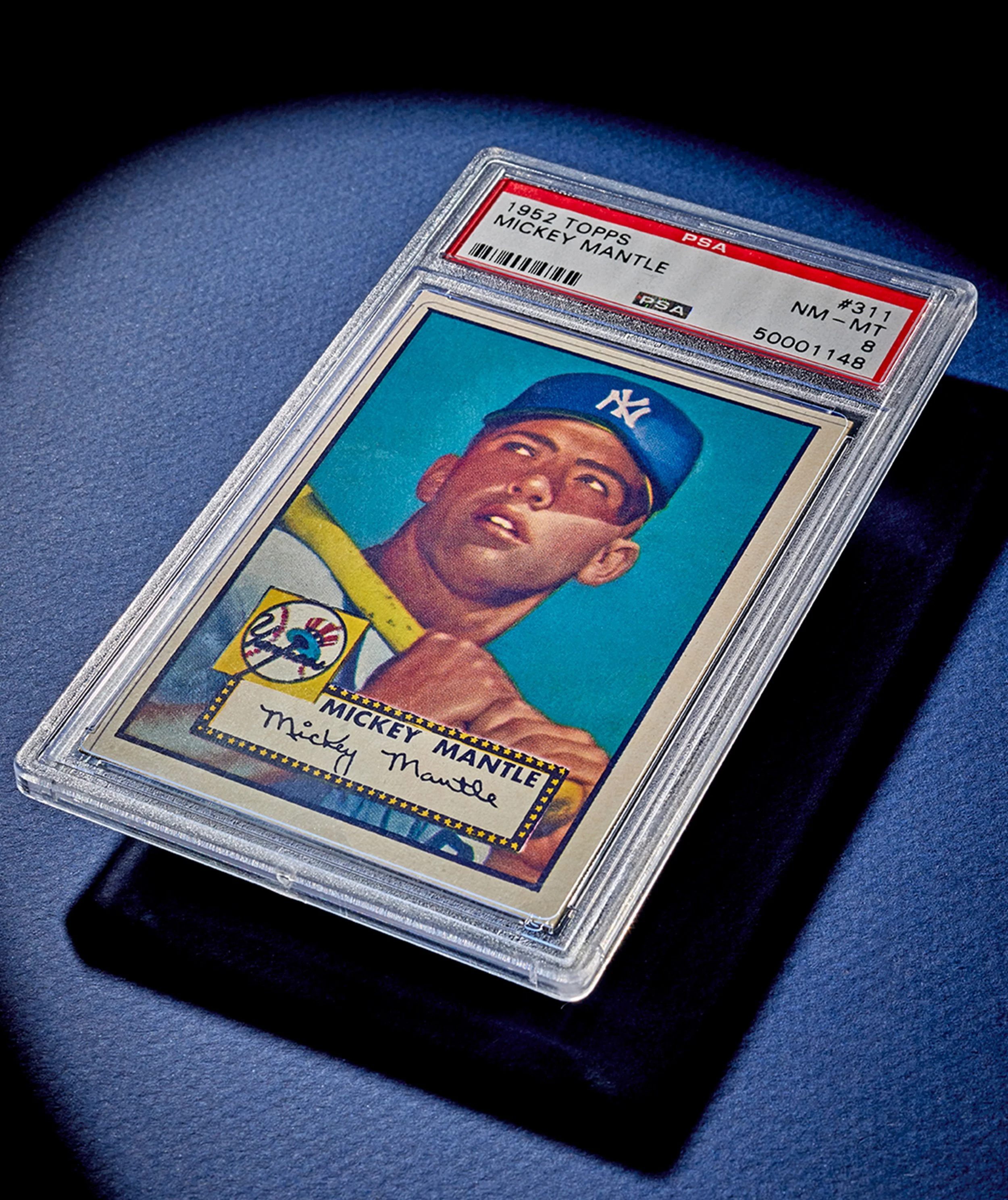 A vintage 1952 Mickey Mantle baseball card encased in a clear protective plastic holder, displayed on a dark surface.