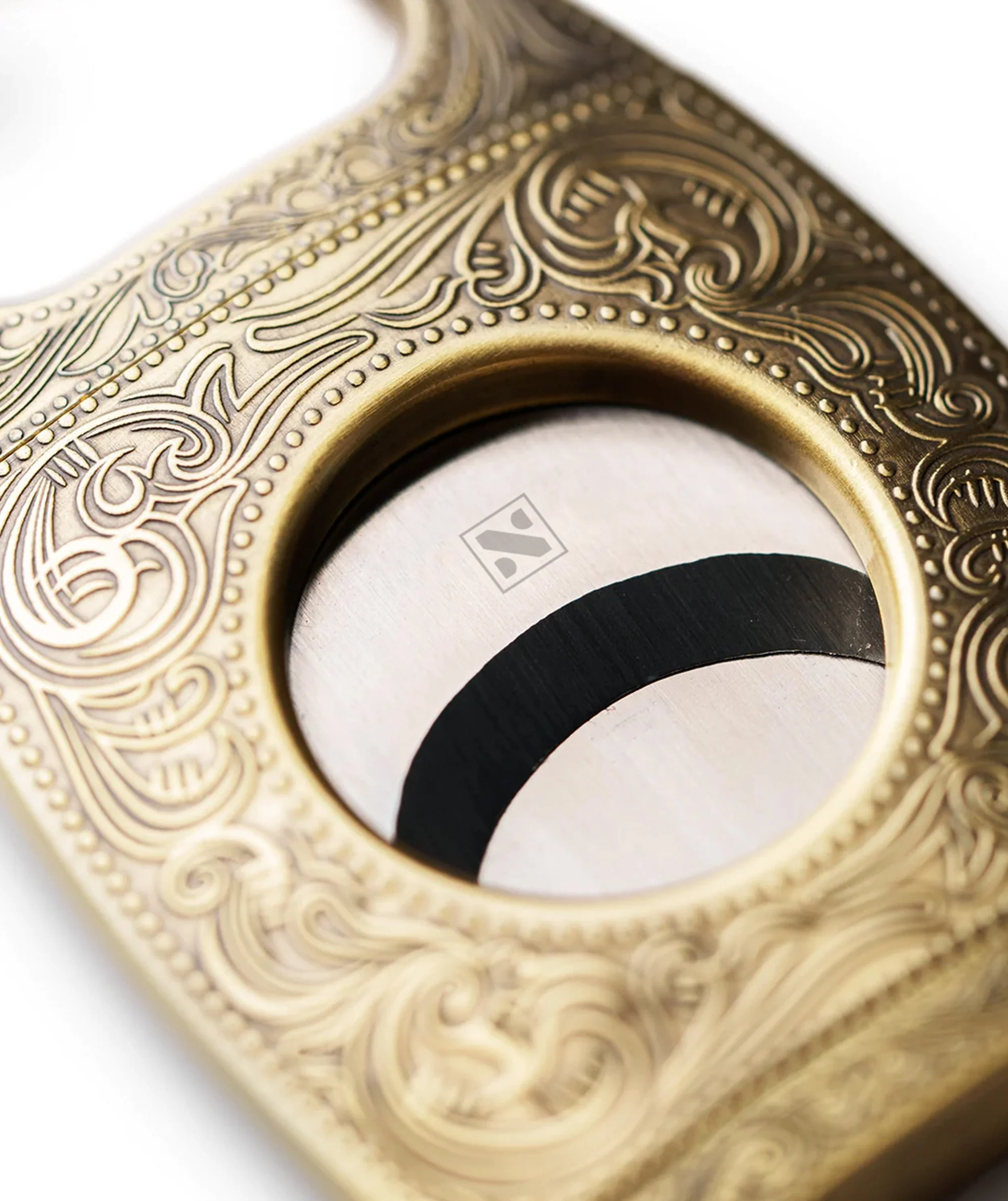 Close-up of an ornate gold-colored object with intricate swirling and dotted patterns, possibly part of jewelry or decorative item.