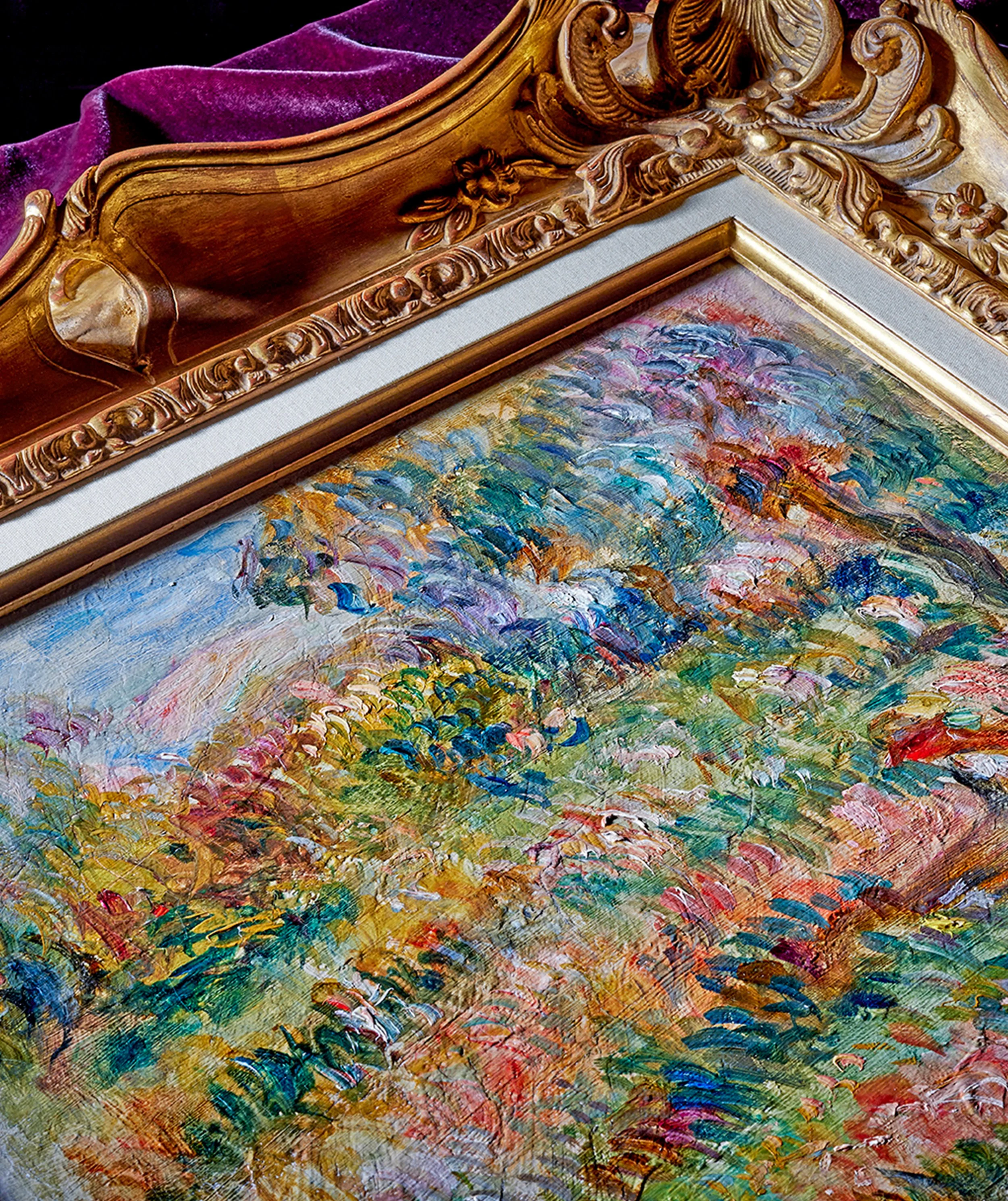 Close-up of a gold ornate frame with intricate floral and scrollwork designs, part of a landscape painting with vibrant, impressionistic brushstrokes of colorful foliage and sky.
