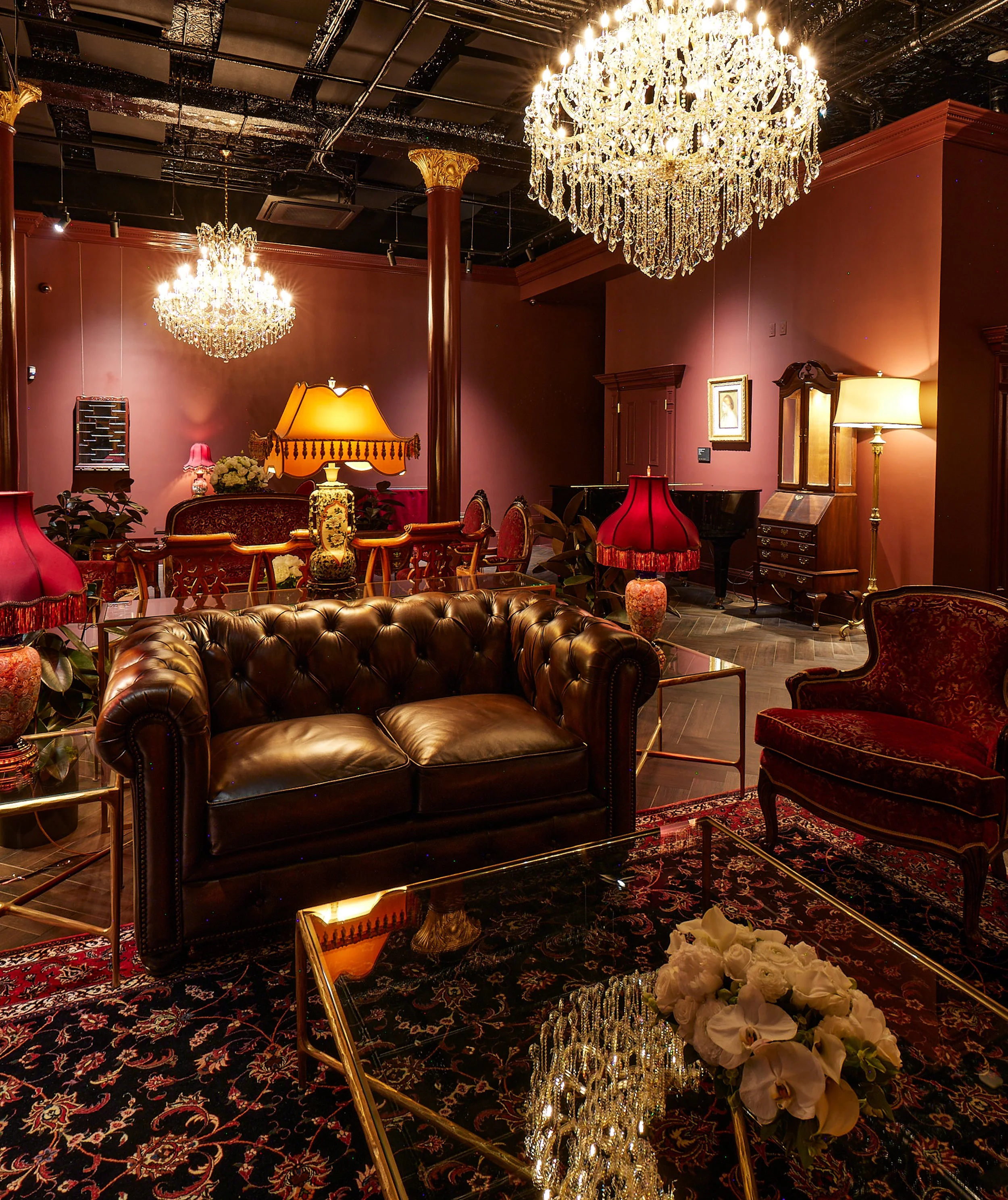 An elegant room with large chandeliers, antique furniture, floral arrangements, and ornate decor, creating a luxurious ambiance.