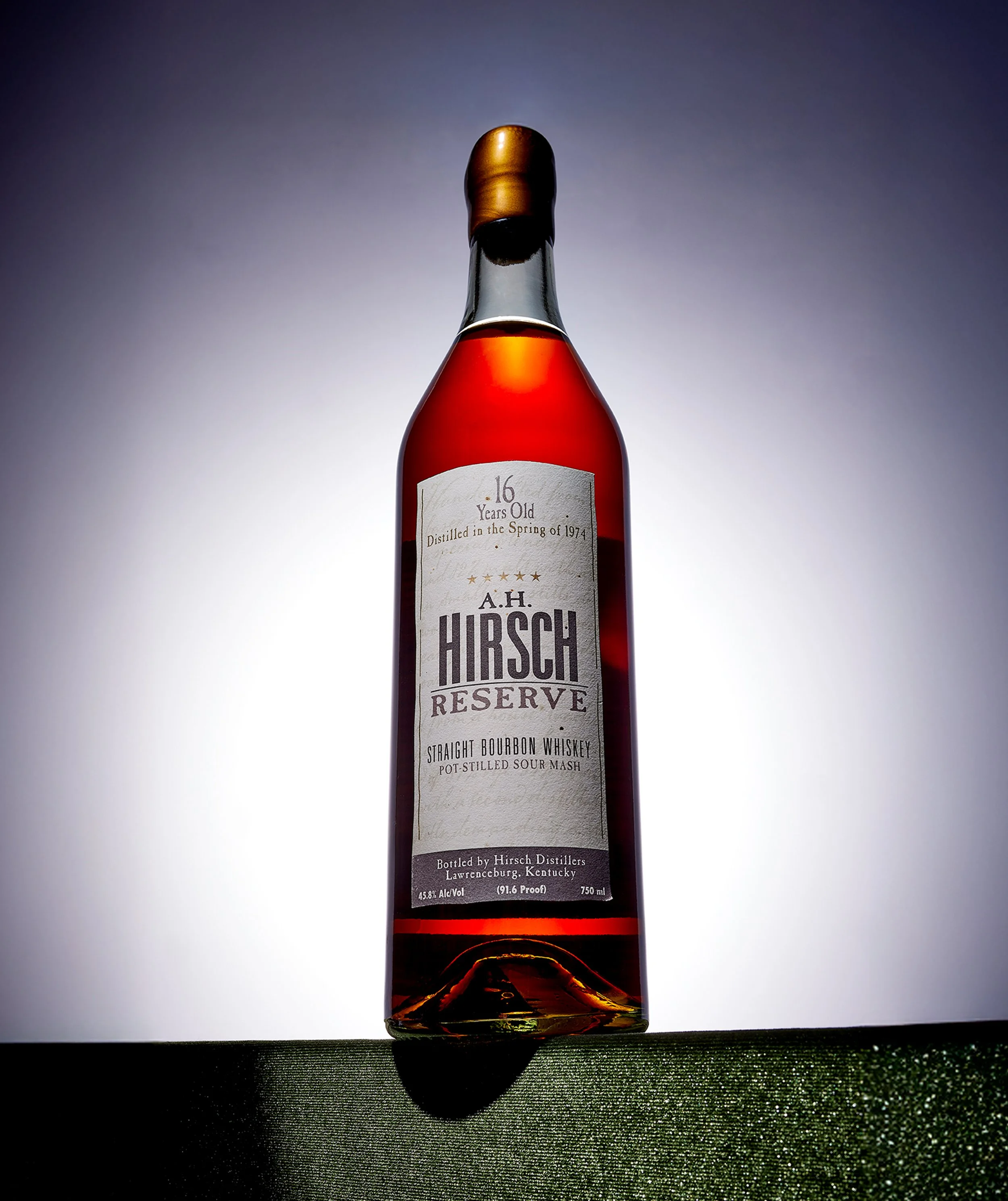 A tall bottle of Hirsch Reserve bourbon whiskey with a white label and a gold cap, standing on a surface with dramatic lighting and a gradient background.