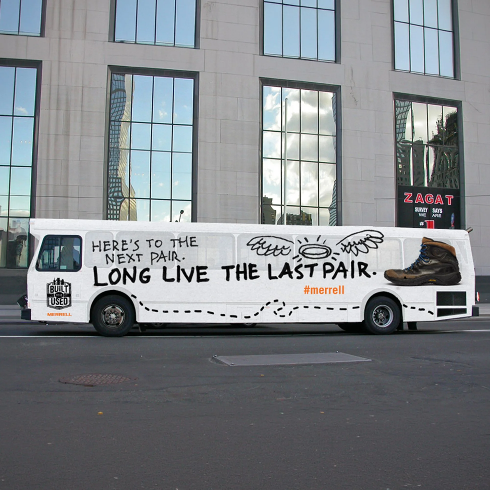 A white vehicle parked on the street with handwritten signs on it, one of which reads 'Here's to the next pair, long live the last pair.' The vehicle has a black sticker that says 'Built for Used' and is branded with 'Merrell.' There are boots placed on the vehicle as part of the display.