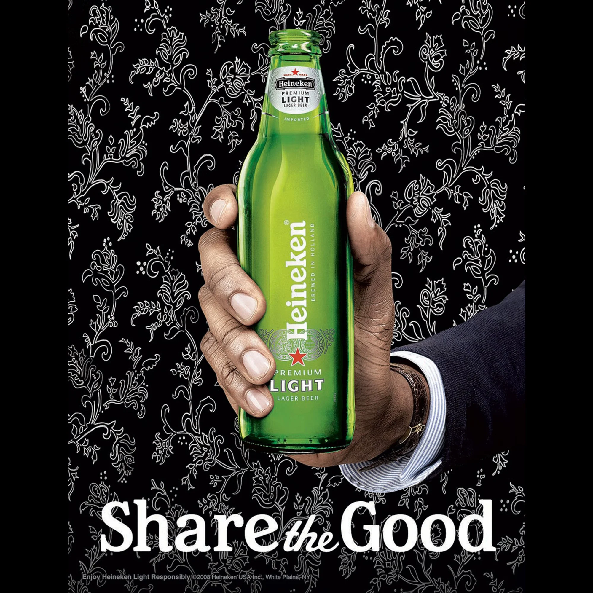 Close-up of a hand holding a green bottle of Heineken Light beer against a black background with white floral line art. The bottle displays the Heineken logo and text indicating it is a premium light lager beer.