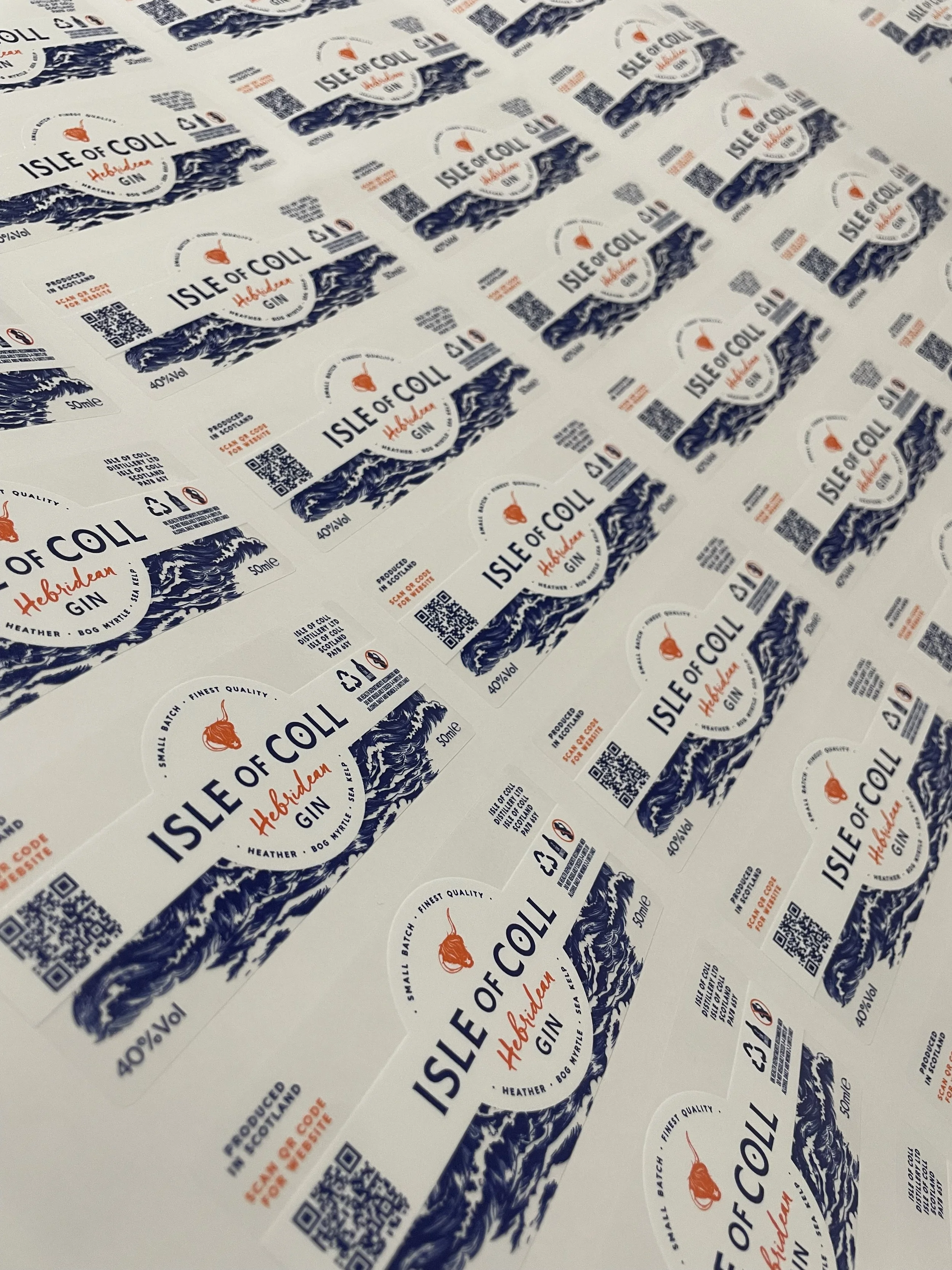 Multiple stickers for Isle of Coll Hibidean Gin featuring a blue mountain landscape, orange gin drop icon, and QR codes.