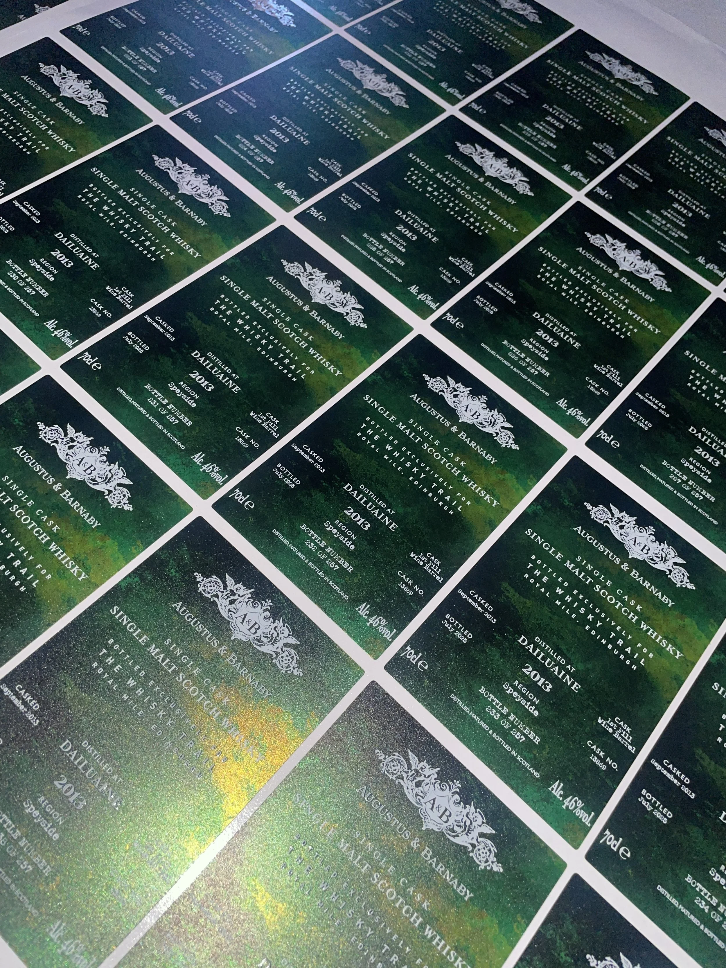 Multiple green and black whiskey labels featuring the brand August and Barnaby, with text detailing the product as single malt Scotch whisky distilled in Dailuaine in 2013, 46% alcohol, and various other details.