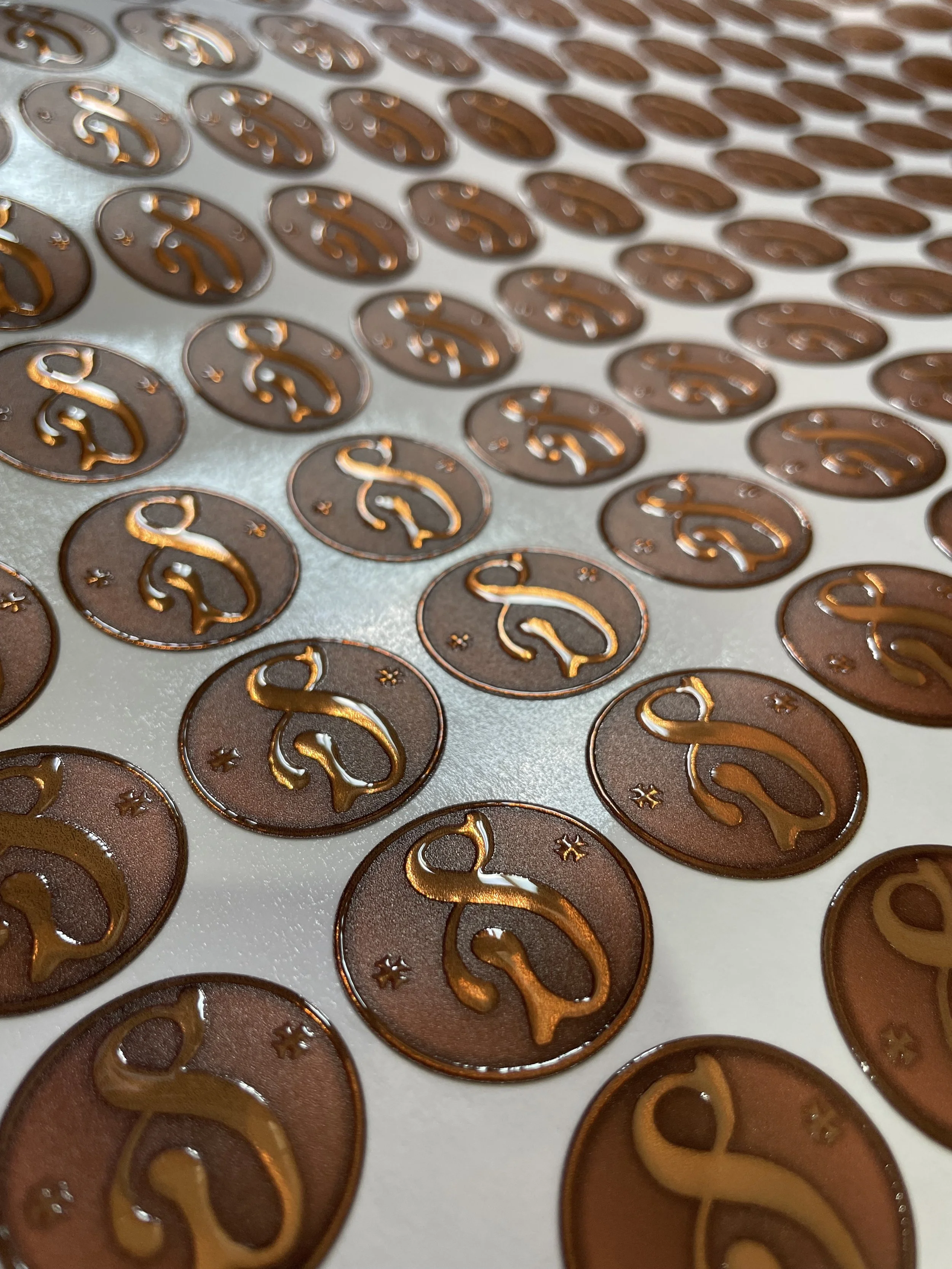 Close-up of metallic circular stickers with a dollar sign symbol and small asterisks on a surface.