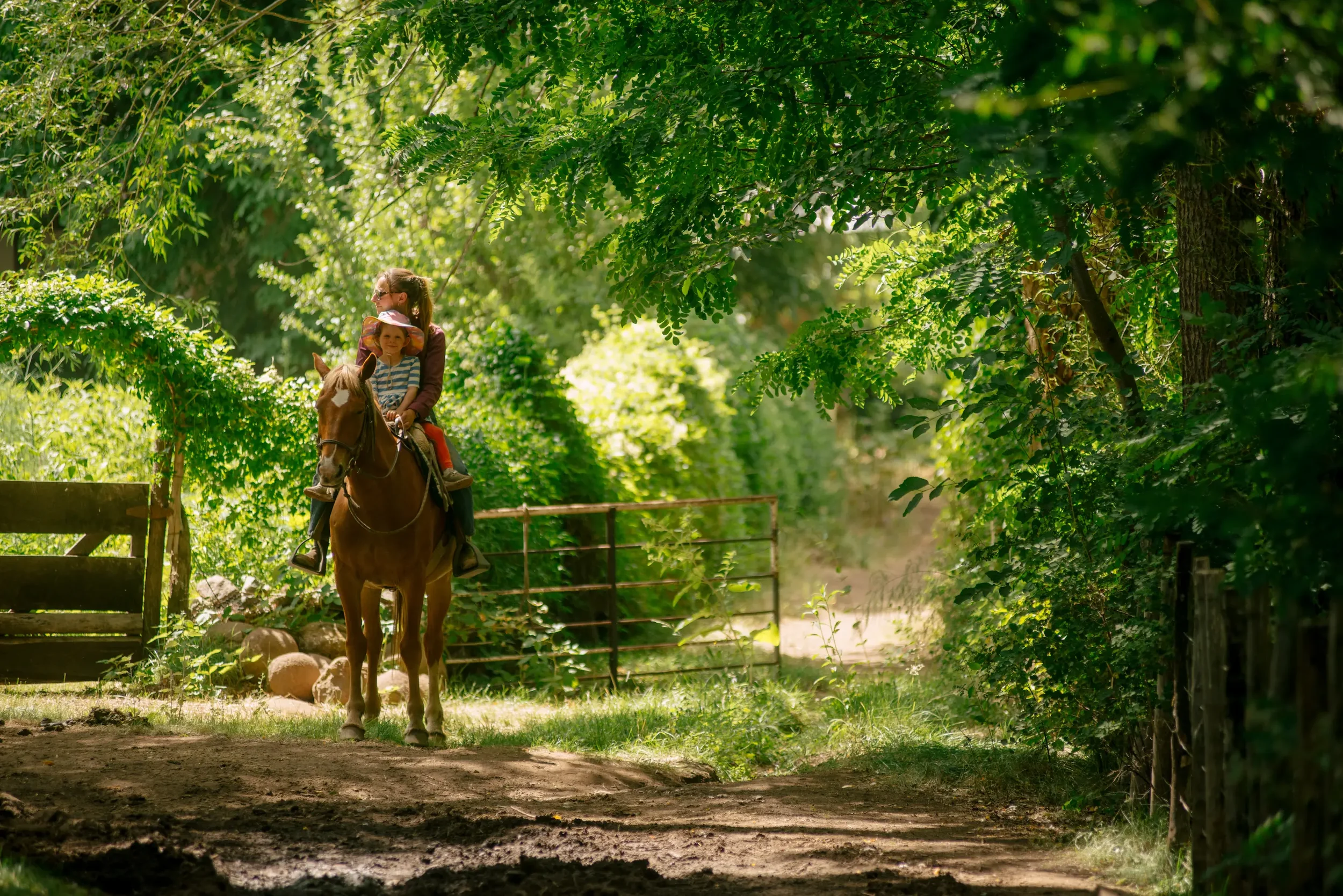 Woman and child riding horseback through the gardens at Estancia Ranquilco, Patagonia