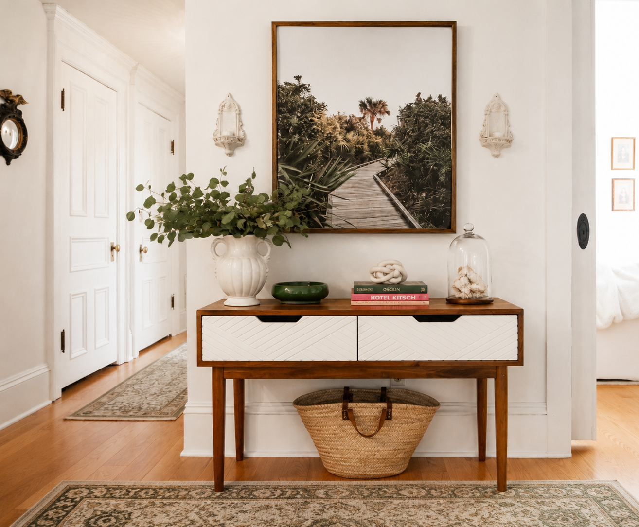 Hallway by Linda McDermott of McDermott Interiors, Portland, OR. A thoughtfully styled hallway featuring a wood console table, oversized black-and-white artwork, sculptural décor, natural greenery, and layered textures that create a warm, welcoming f