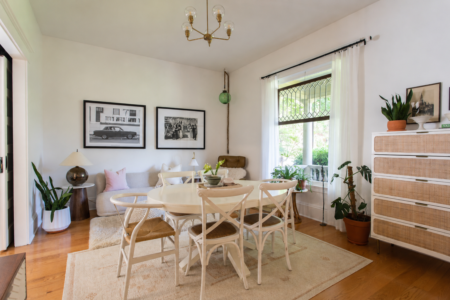 Portland, OR living and dining room designed by Linda McDermott of McDermott Interiors, featuring warm hardwood floors, a comfortable sofa, dining area, black-and-white photography, natural greenery, and woven textures. This Portland interior design 
