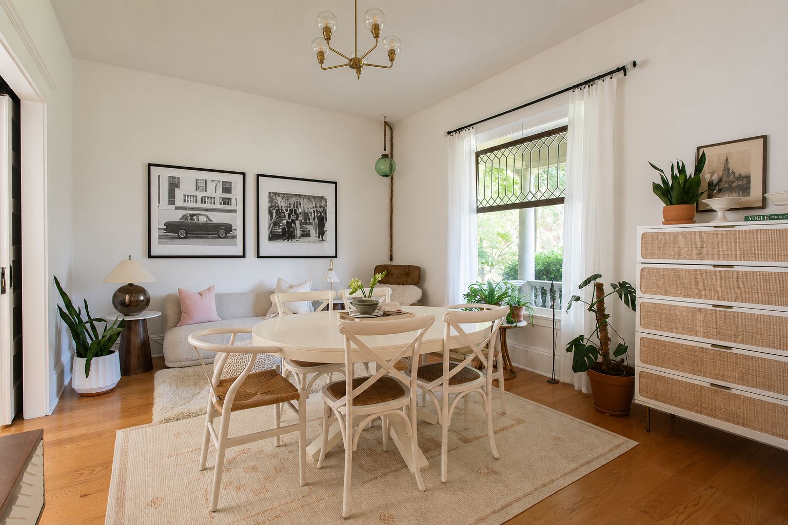 Living and dining room by Linda McDermott of McDermott Interiors, Portland, OR. A bright, inviting space featuring a white round dining table, upholstered chairs, a neutral sofa, curated artwork, lush greenery, and large windows.